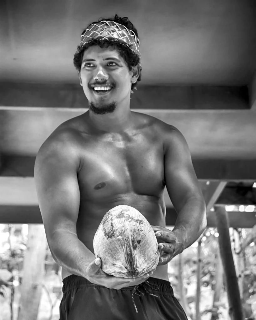 Cook Islands local man presenting a fresh coconut in Rarotonga village setting