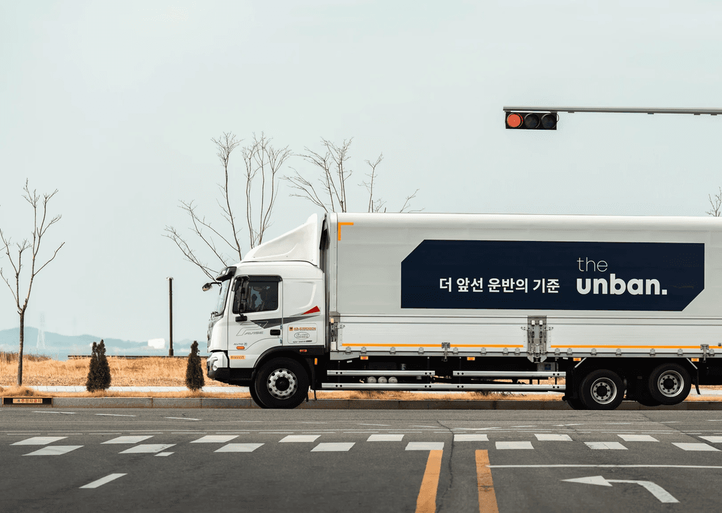 씨제이대한통운 더 운반 운송 차량이 도로 위를 주행하고 있습니다.