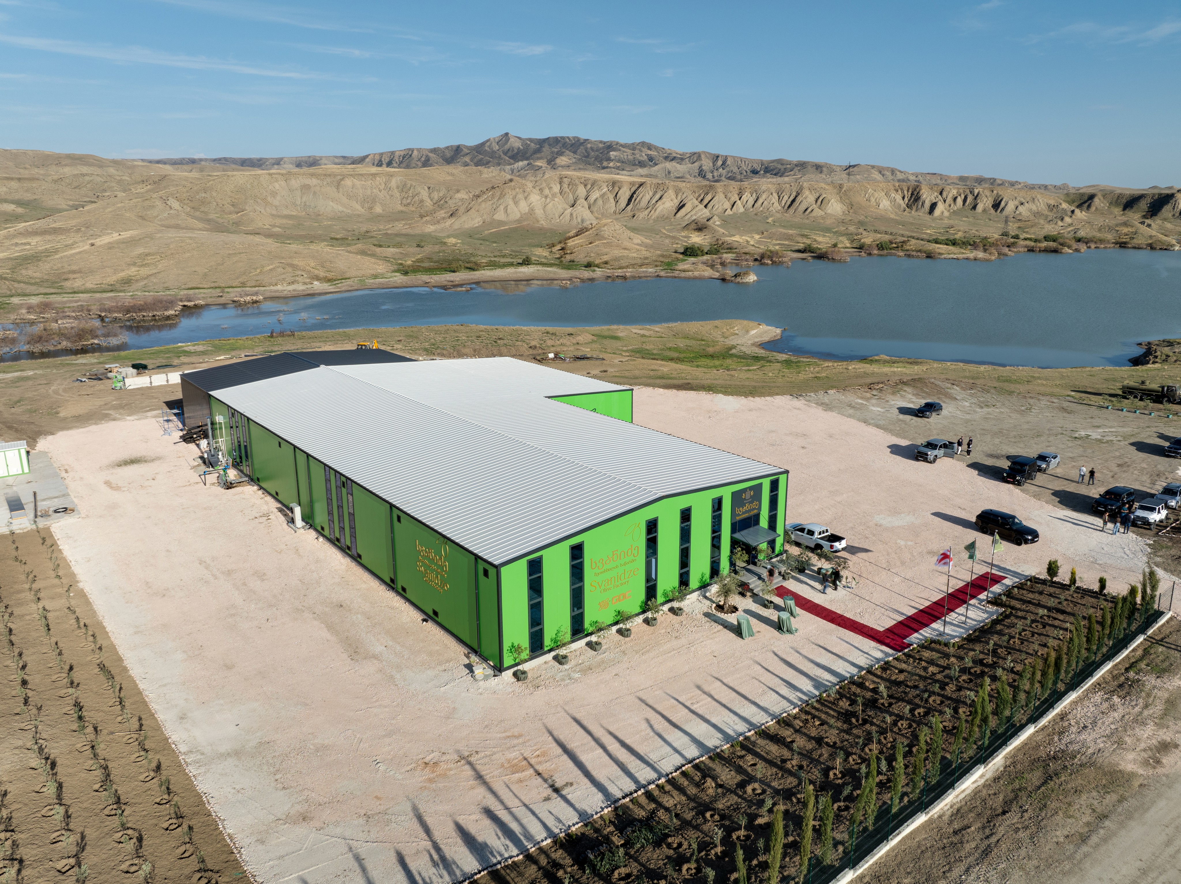 A smiling young man with crossed arms, wearing a plaid shirt and white t-shirt, poses against a dark background.