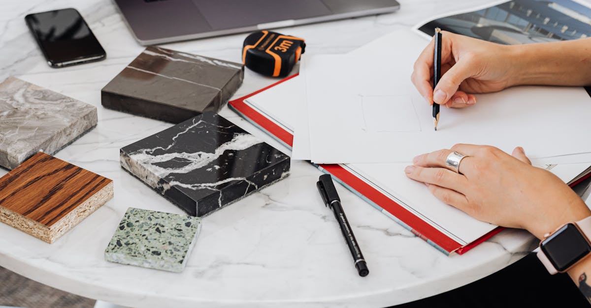 Architect works on design with material samples, sketching ideas on a marble table.