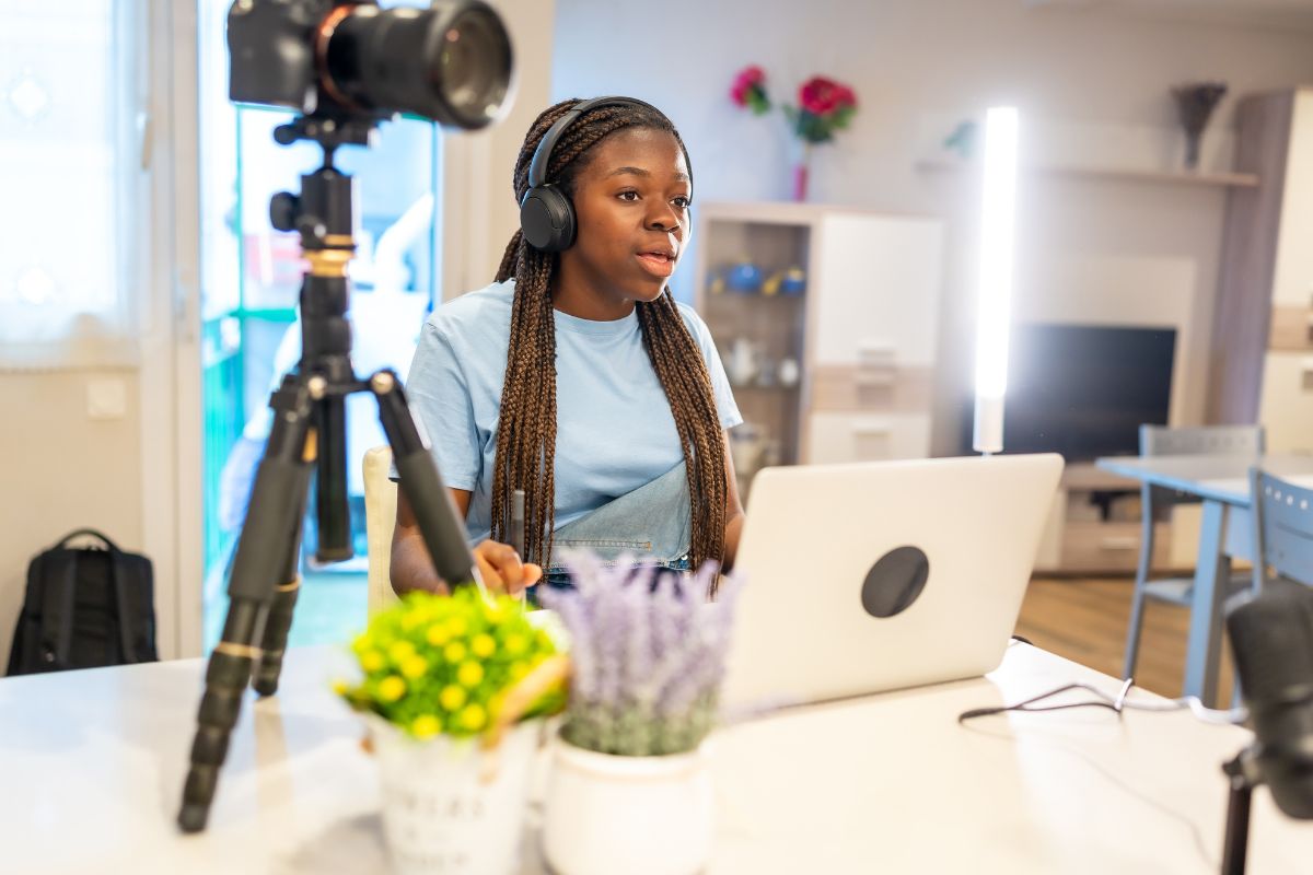 Person using a laptop and camera in an office.