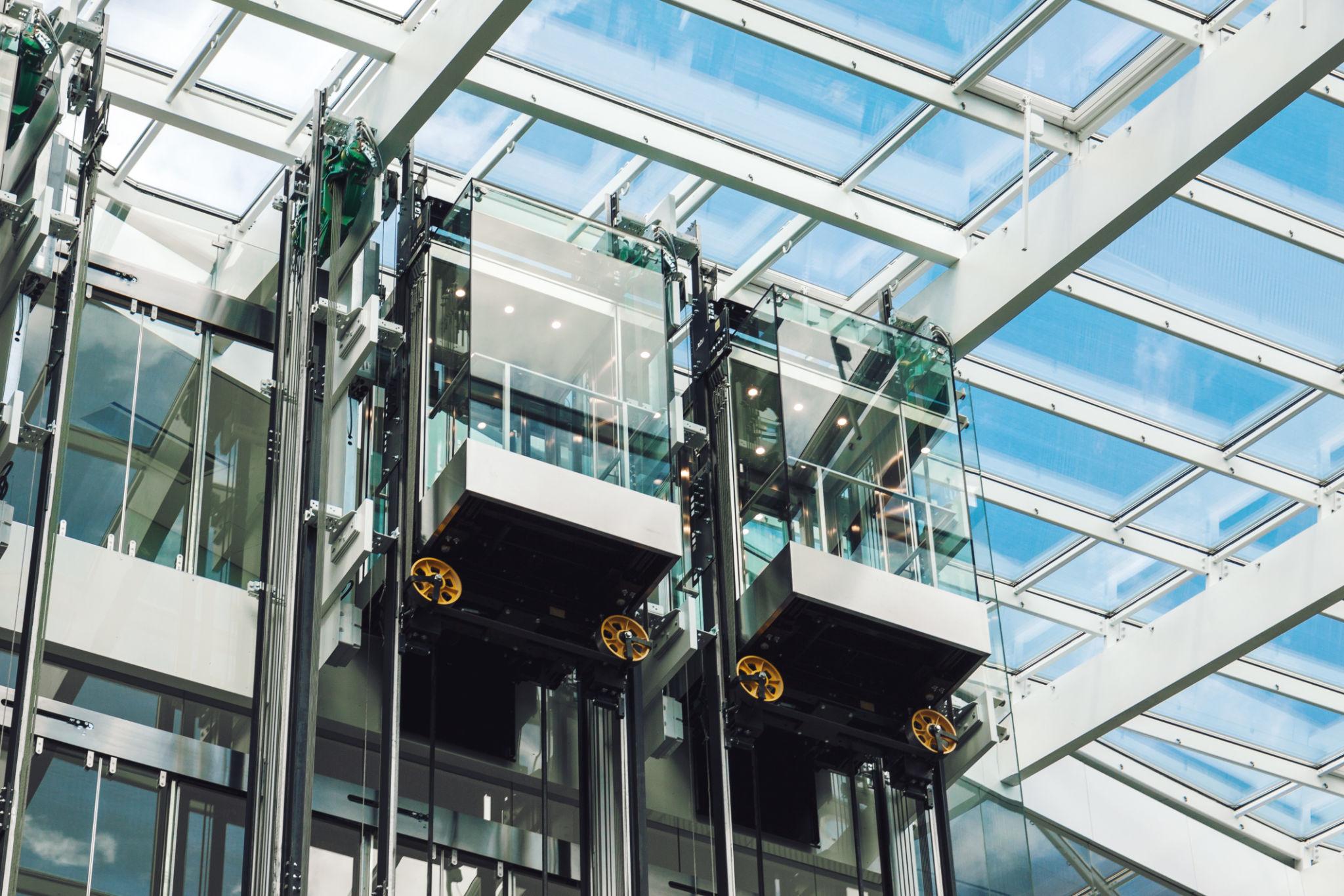 glass elevators inside a bright, modern building atrium