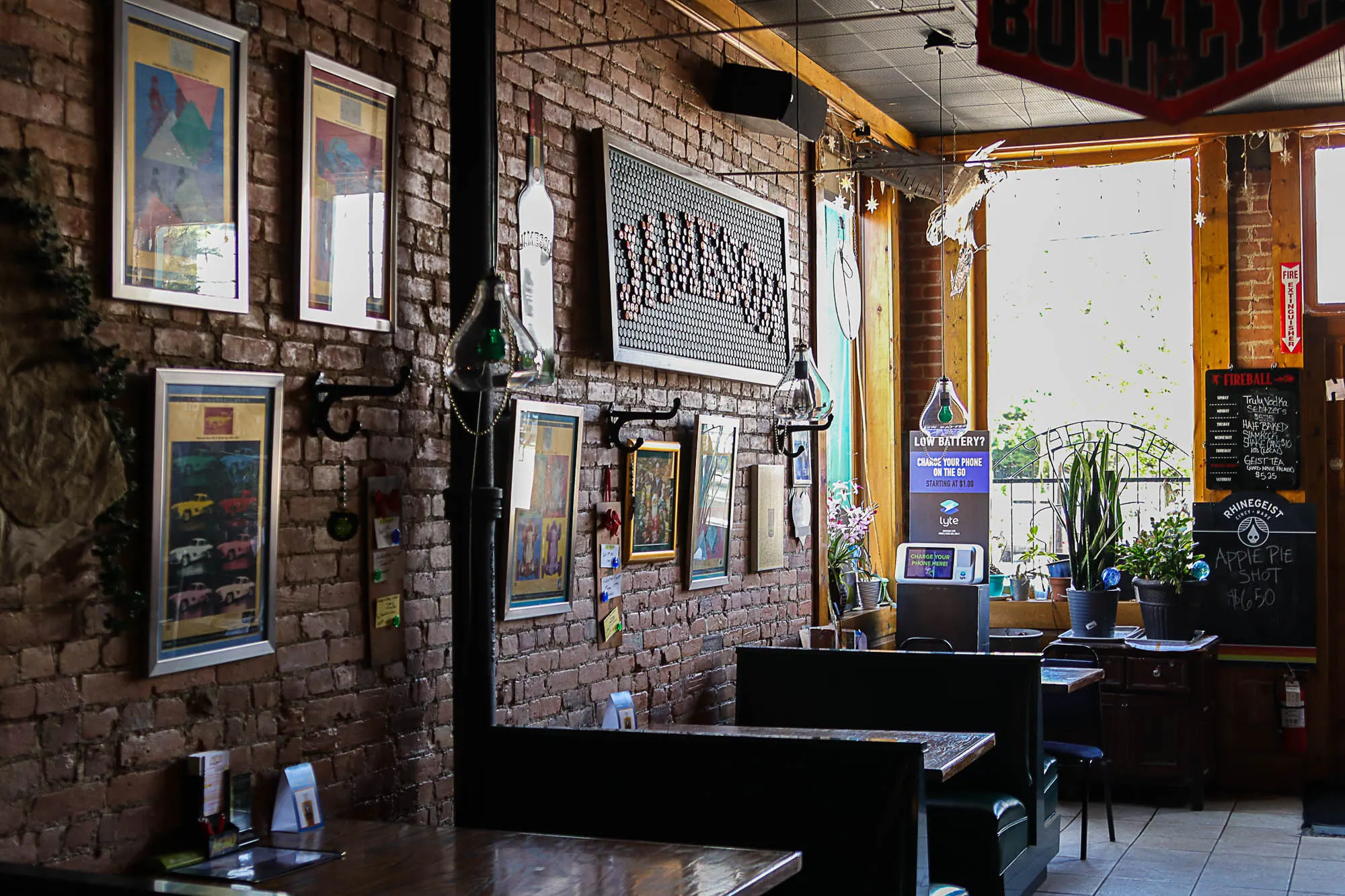 Brick wall with framed art and wooden tables at Hey Hey