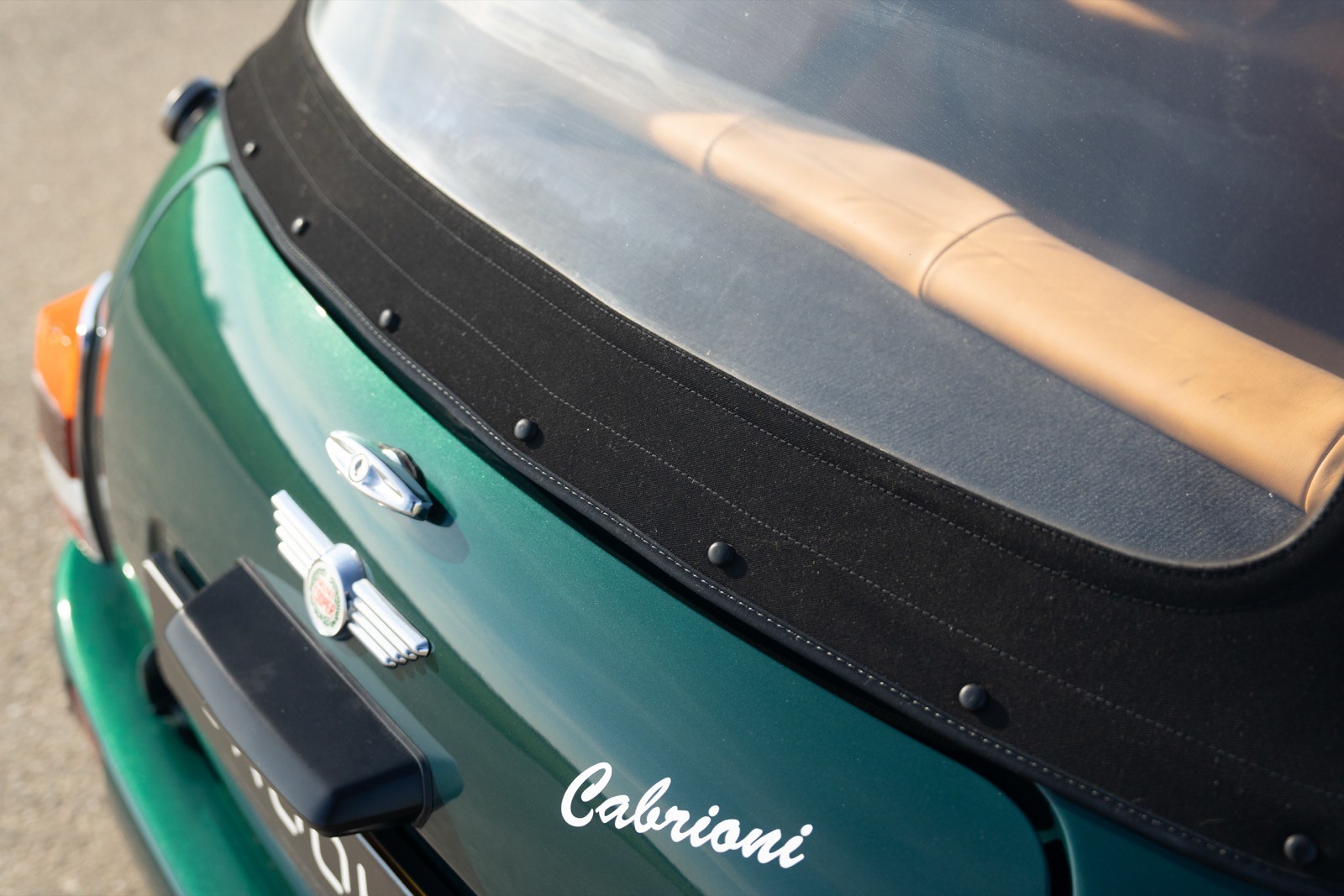 A close-up of the rear of a green car, showing the back window and part of the trunk lid.