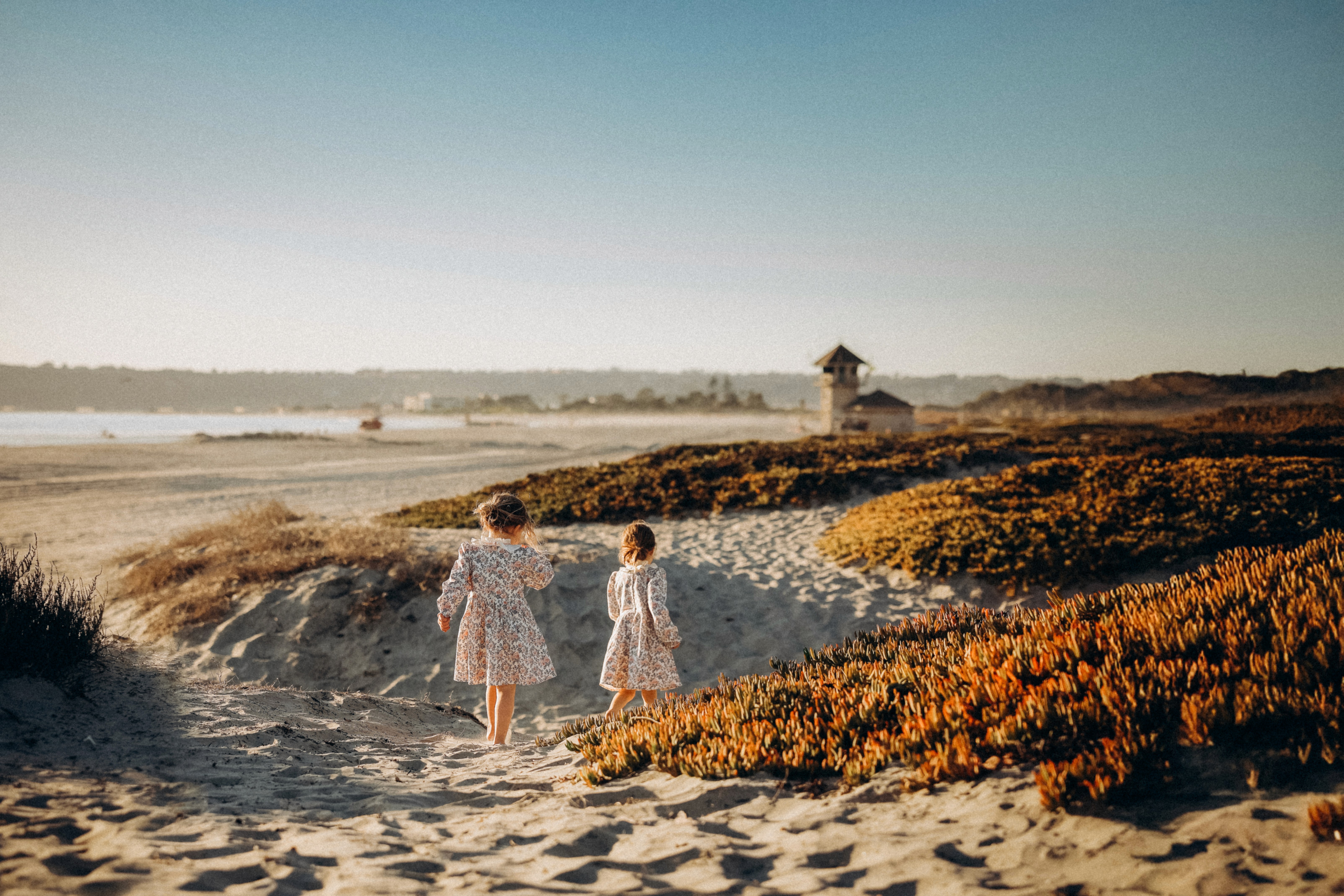 Siblings walking together on a sandy trail at sunset in San Diego.
