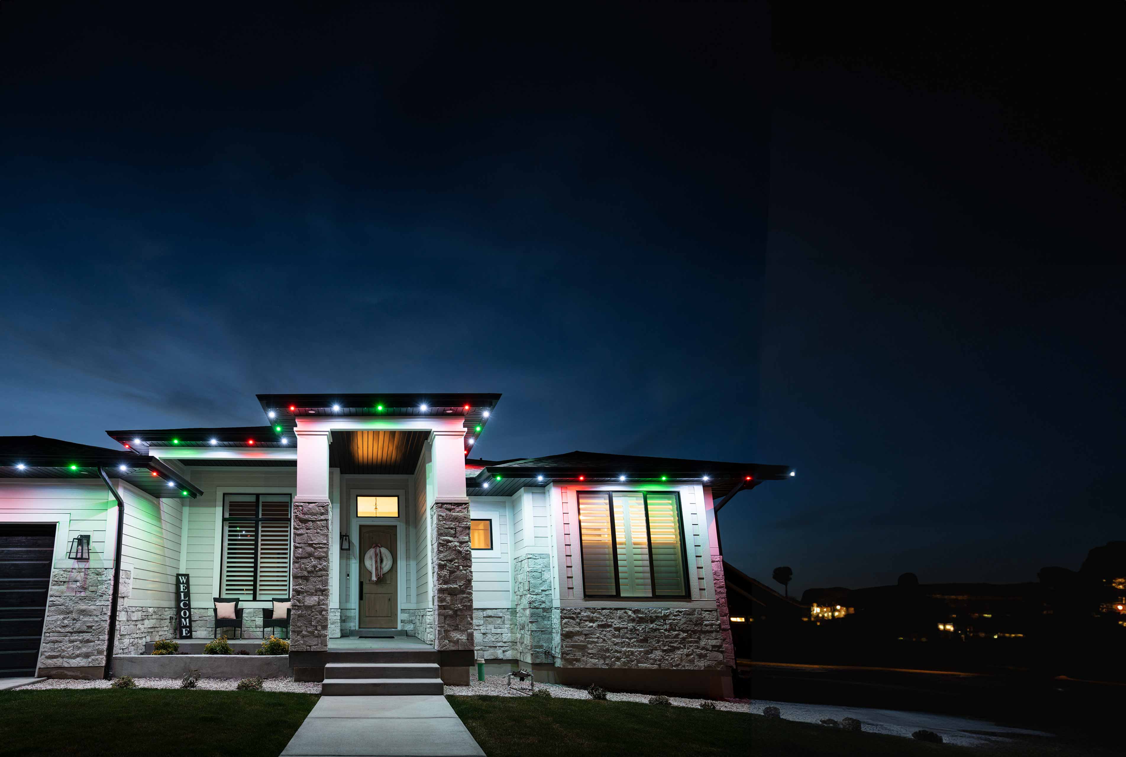 A house at night with white red, white, and blue Christmas lighting going along the roof trim