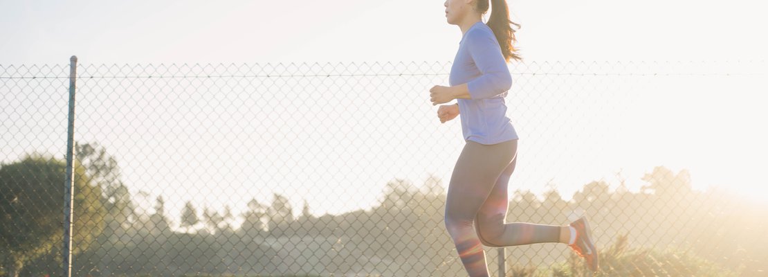 a woman jogging in front of a fence