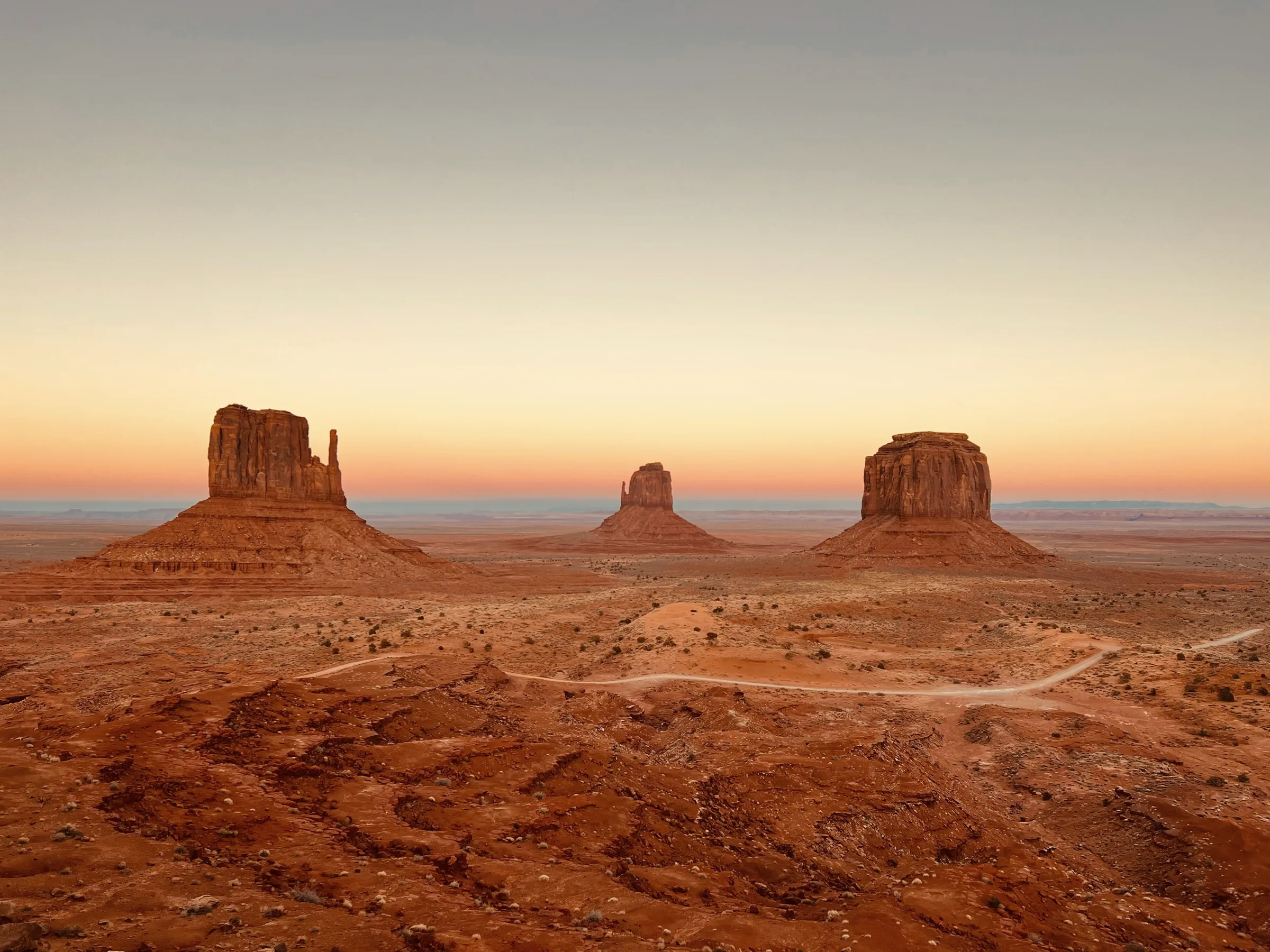 Three buttes over a red desert at dawn