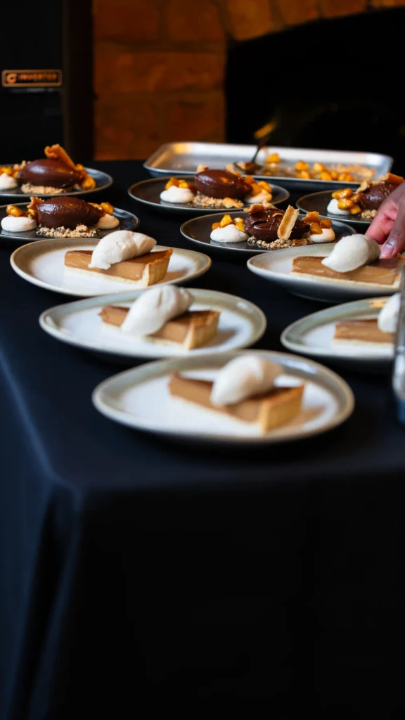 Rows of desserts plated on black linen ready for service