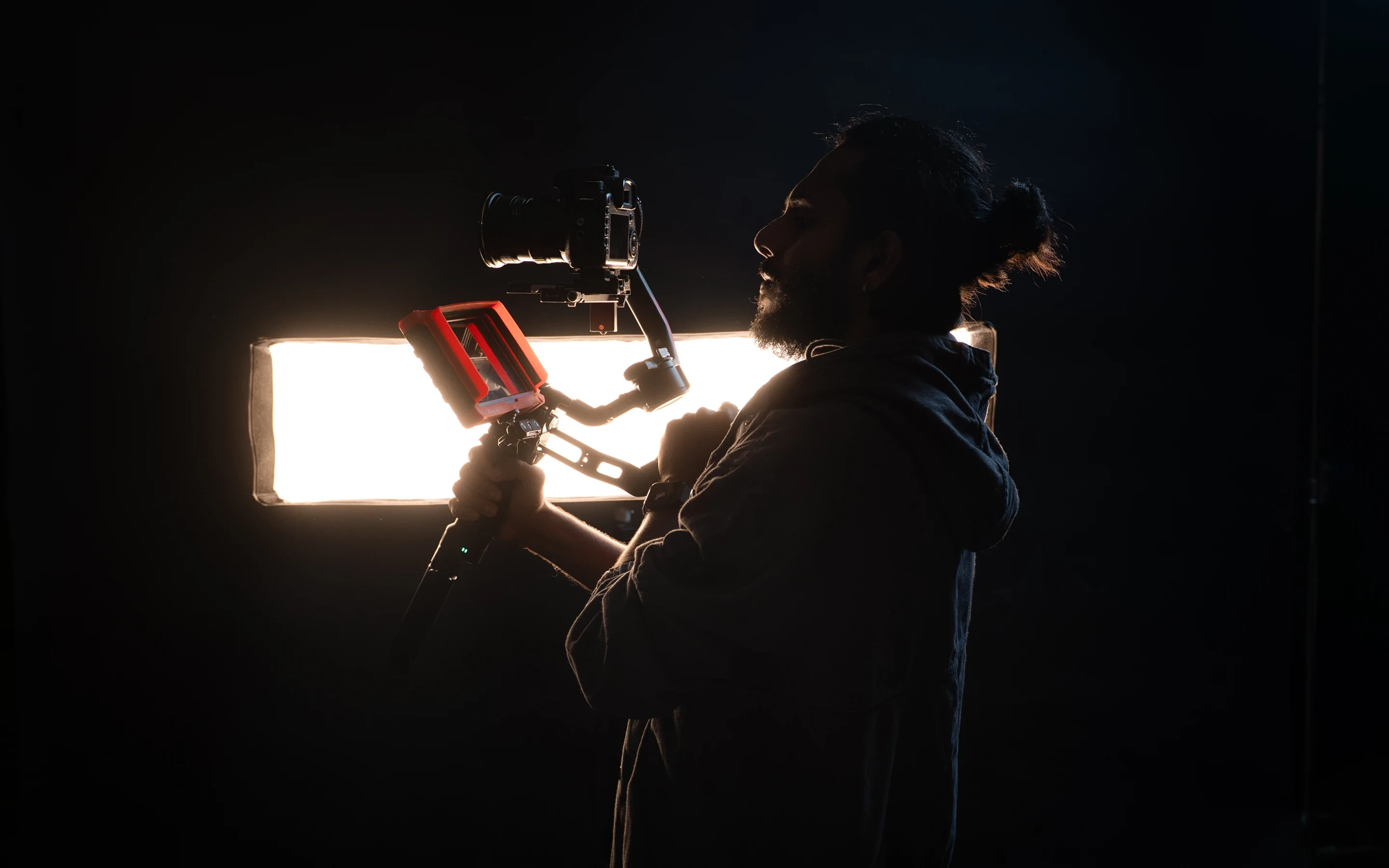 The men in dramatic lighting collaborate closely during a setup for a corporate video shoot
