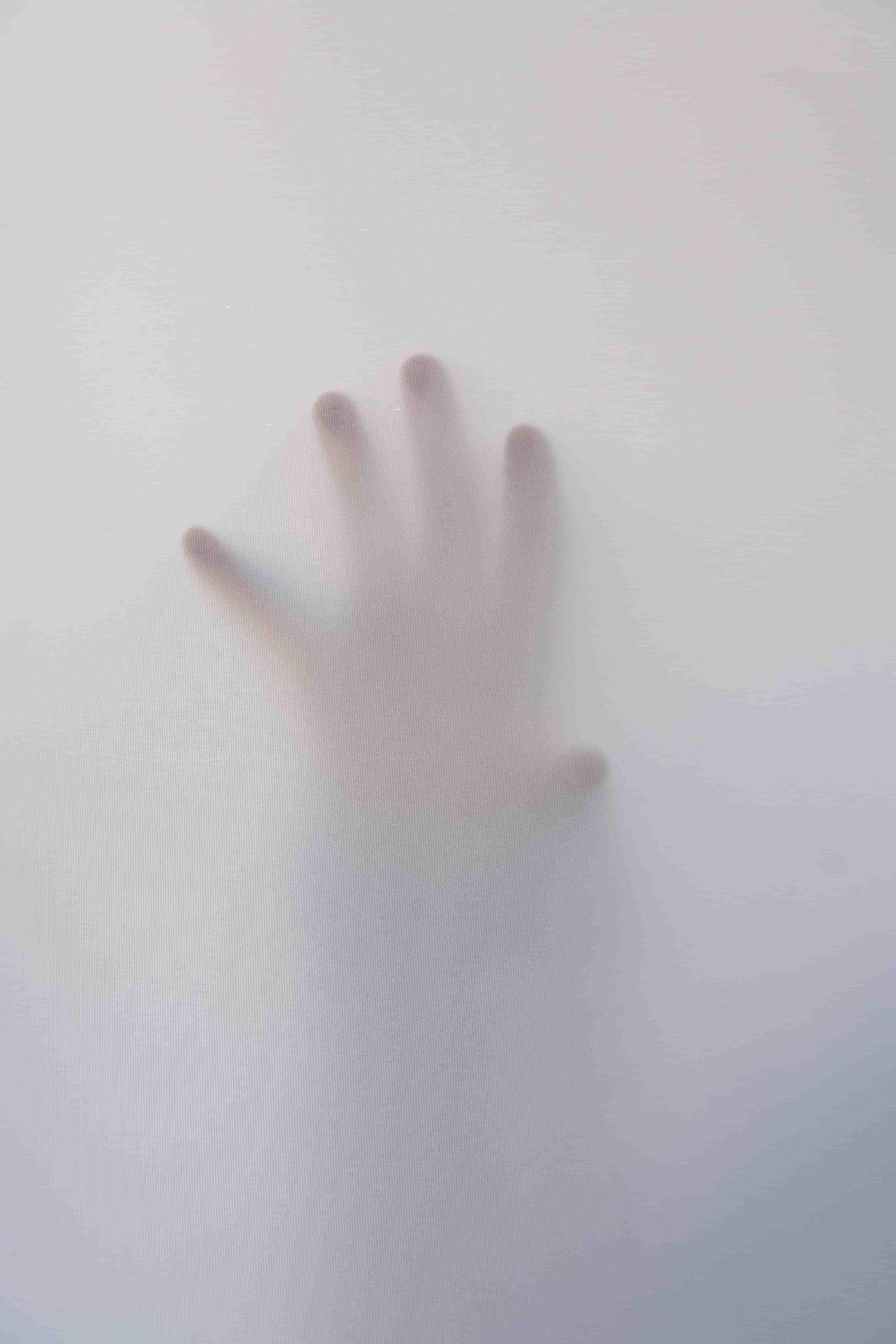 An image of a hand touching frosted glass