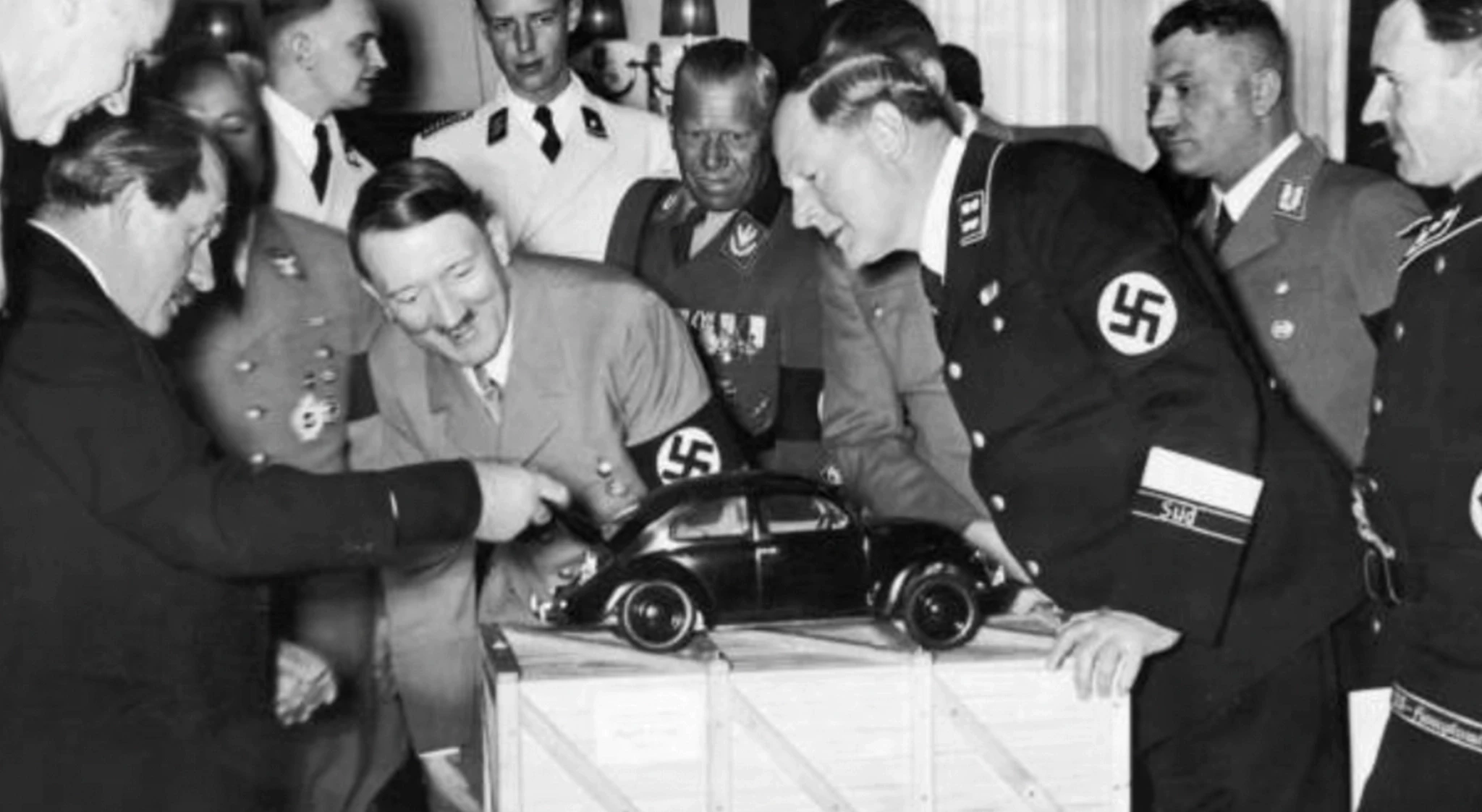 Ferdinand Porsche alongside members of the Nazi Party including Adolf Hitler, discussing the beloved Volkswagen Beetle