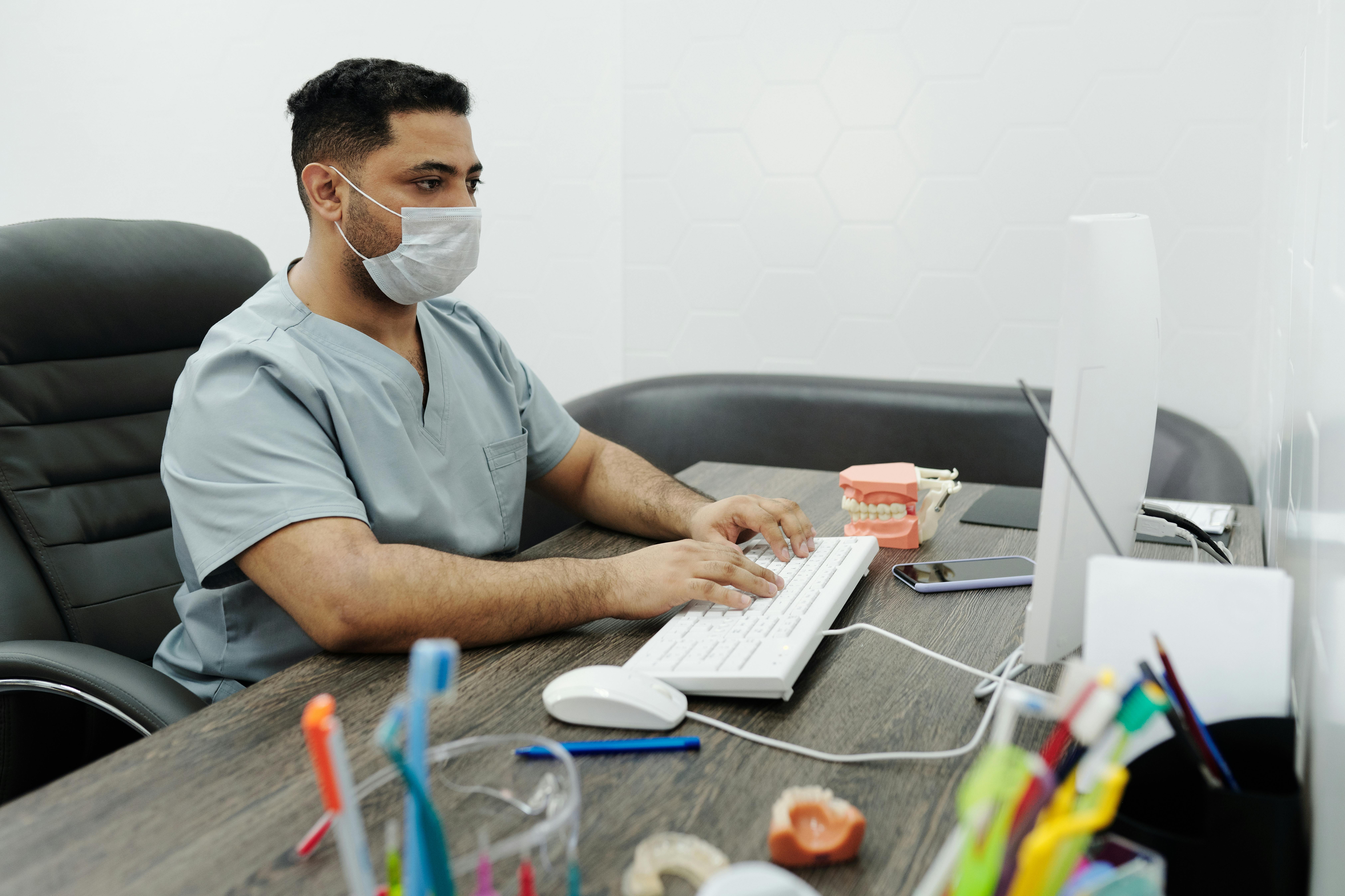 dental hygienist sits at computer at the front desk of a dental practice