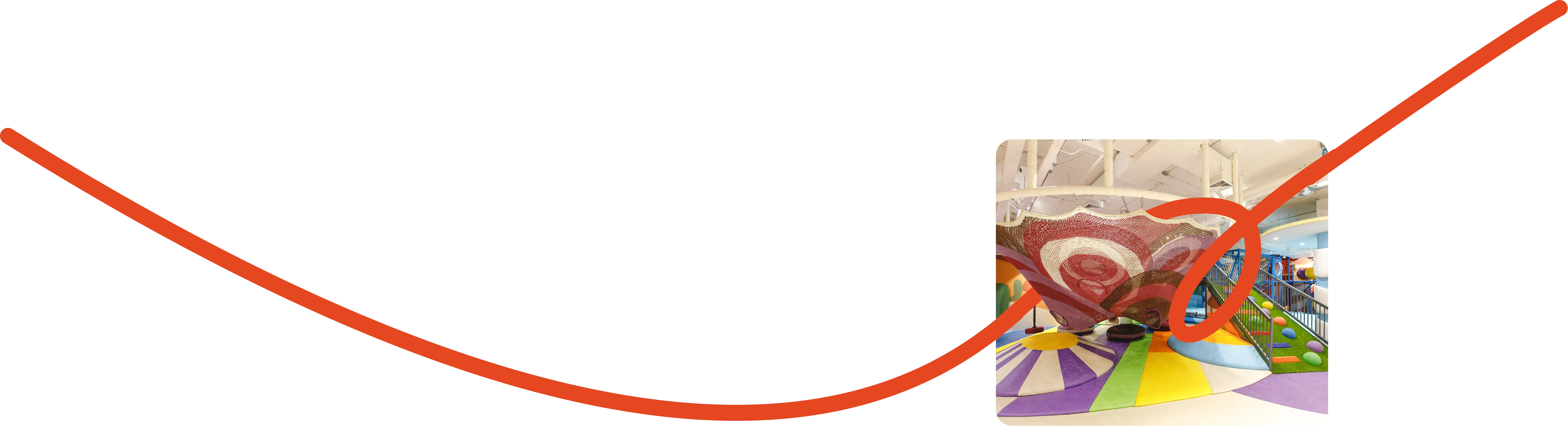 Colorful playground with green structures, a large clock, flowers, and city skyline in the background.