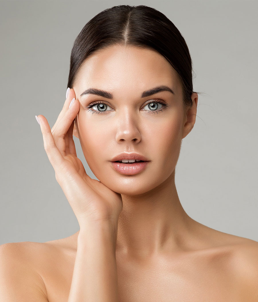 &nbsp;A young woman with flawless skin touching her face, showcasing the benefits of PDO threads for facial rejuvenation.