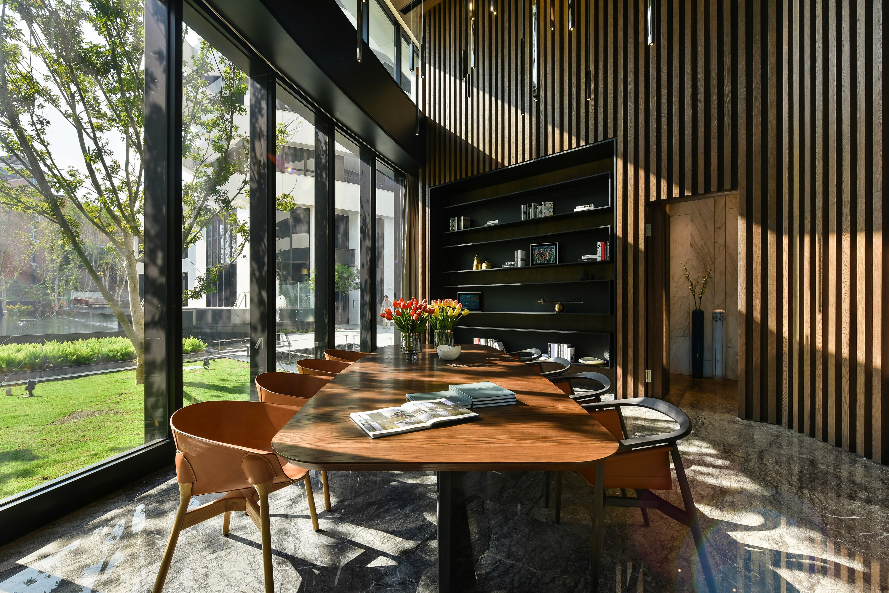 Wood-paneled interior with a large window overlooking a garden and buildings.