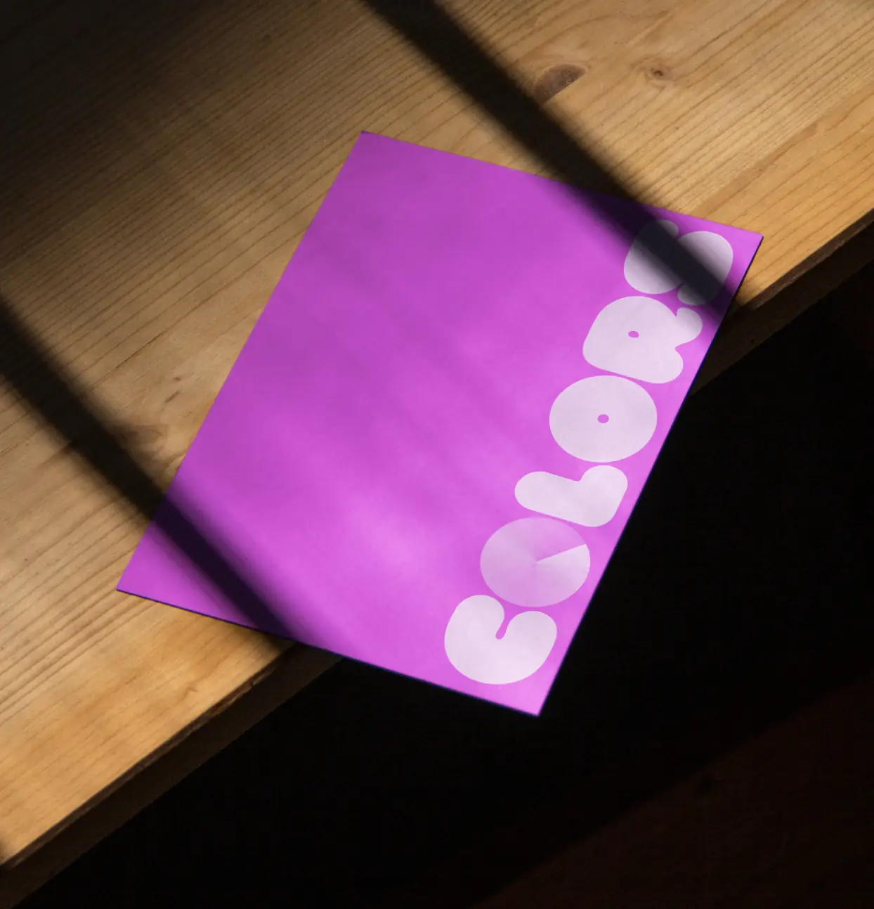 Purple folder on a desk with a sticker sheet from the COLORS visual identity system.