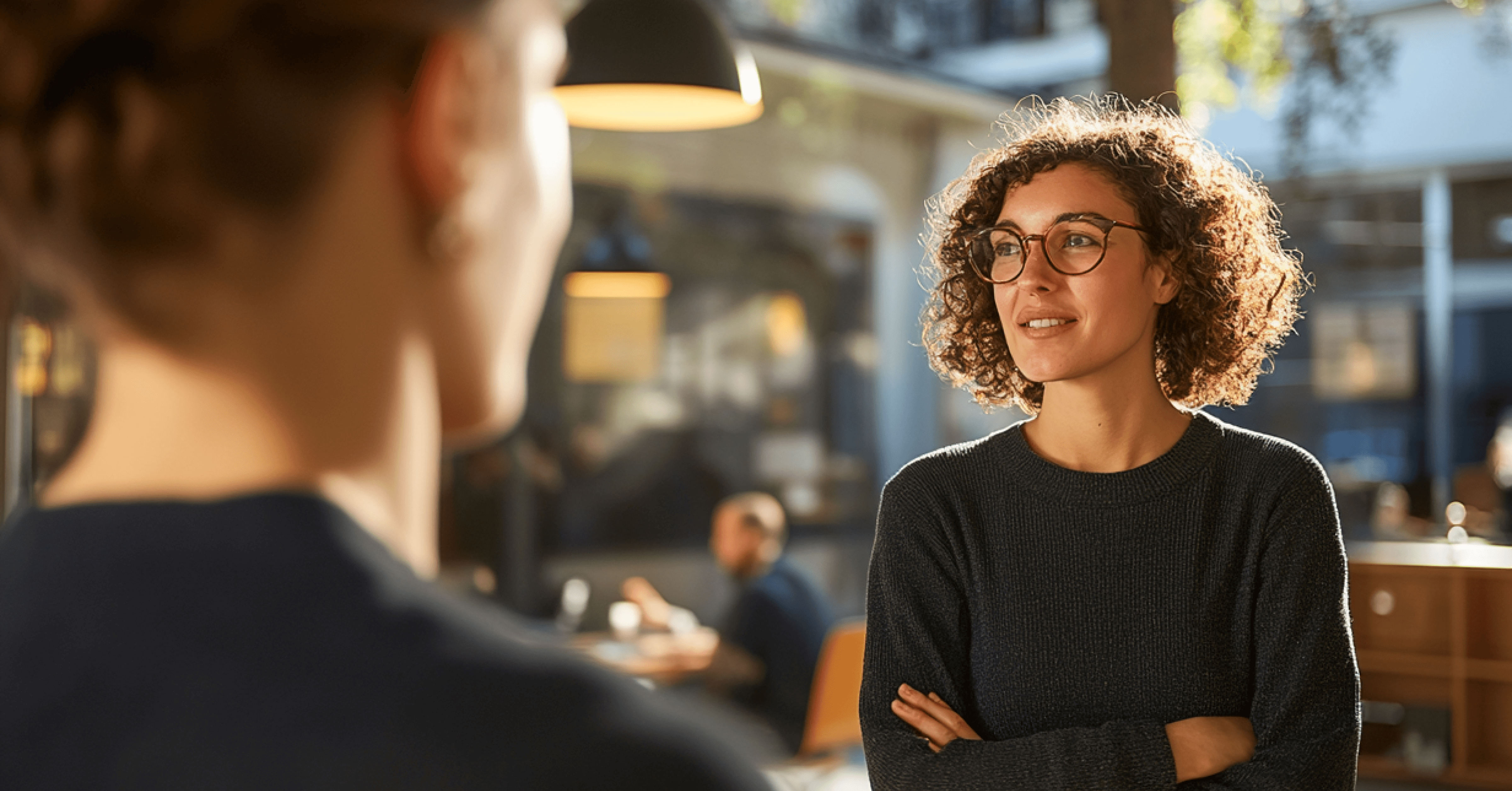 Image of two people standing outdoors, engaged in conversation.