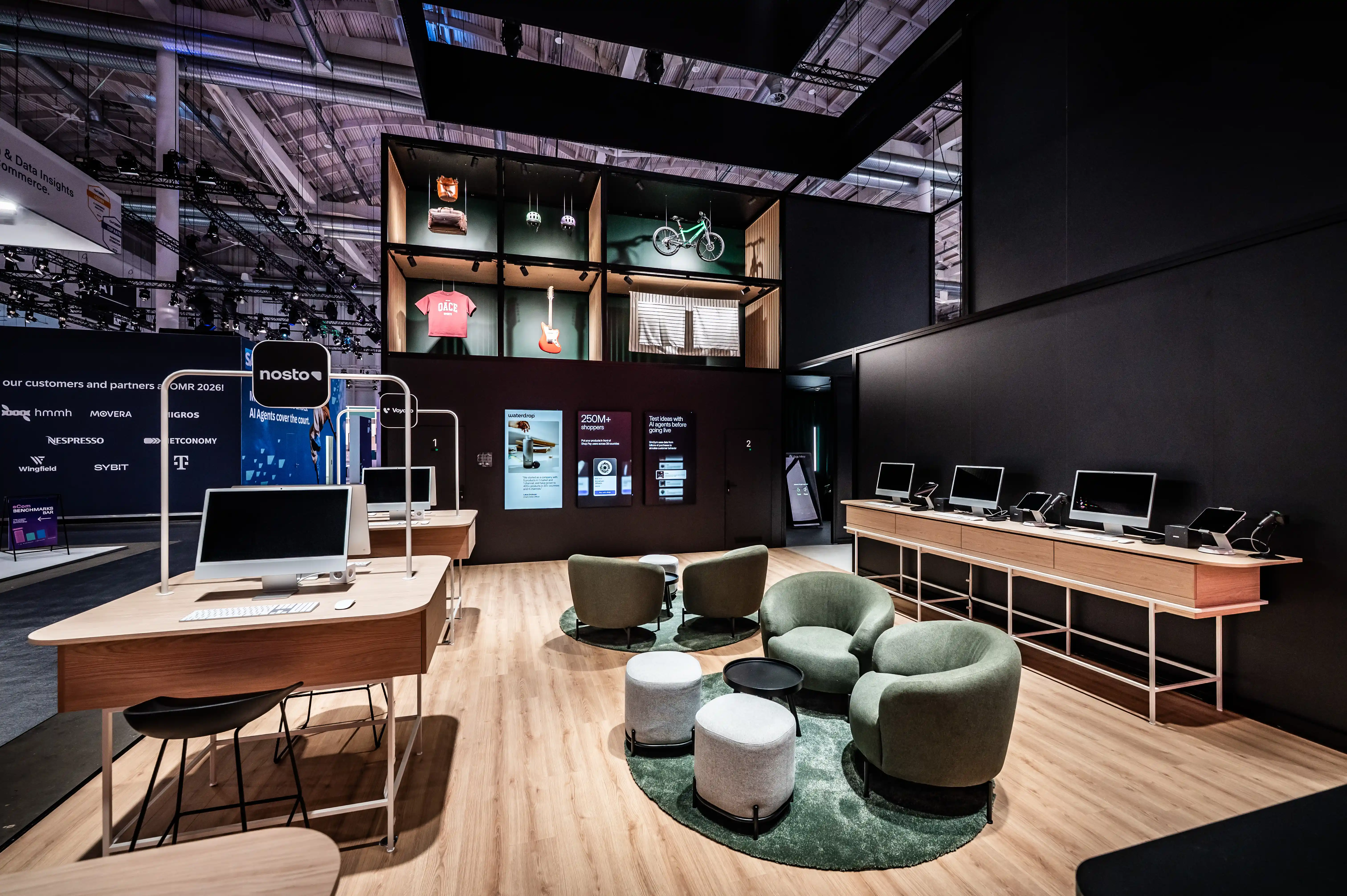Shopify booth interior with green armchairs, wooden desks, display shelf and partner wall.
