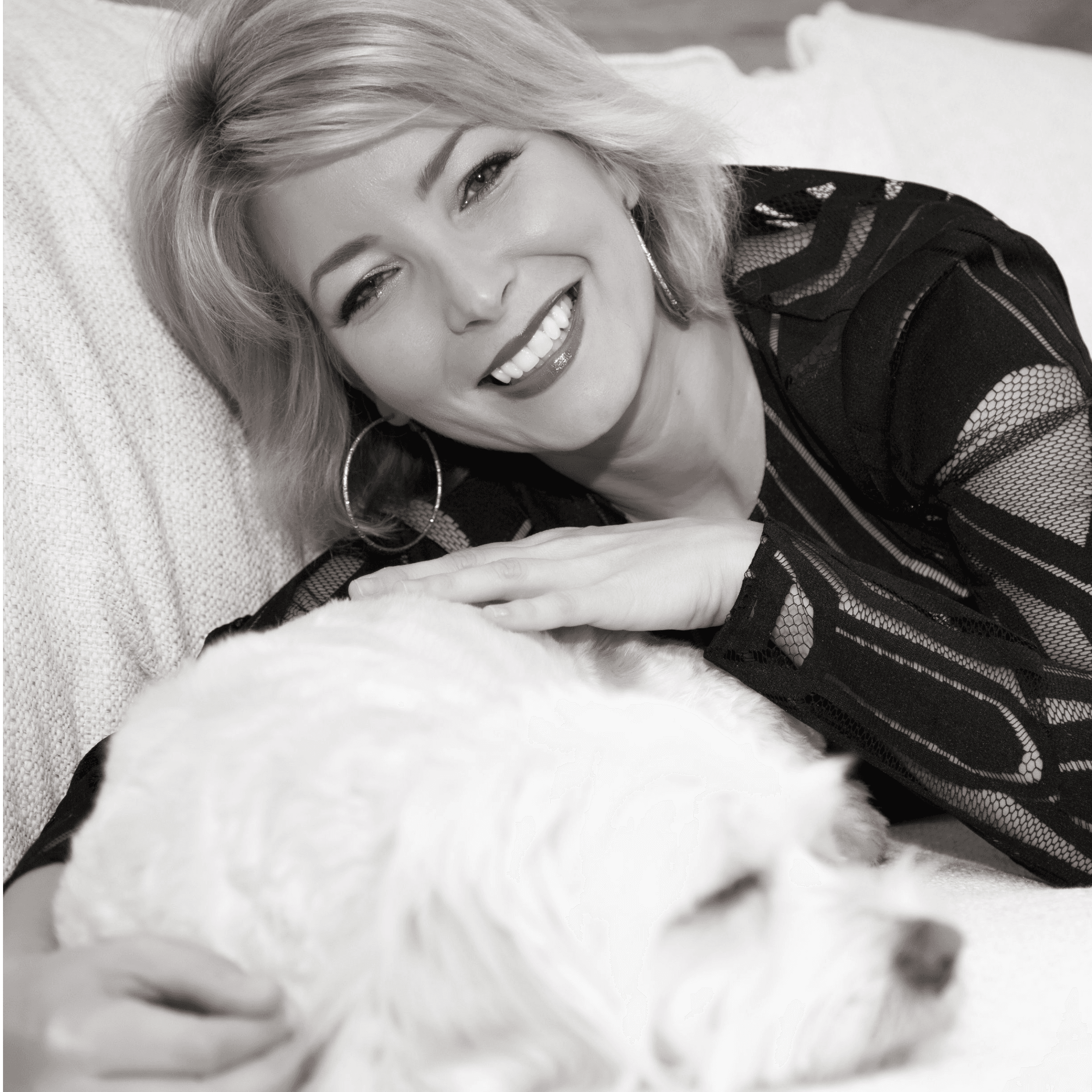 Black and white photo of Cheryl Carreau smiling with her white dog.