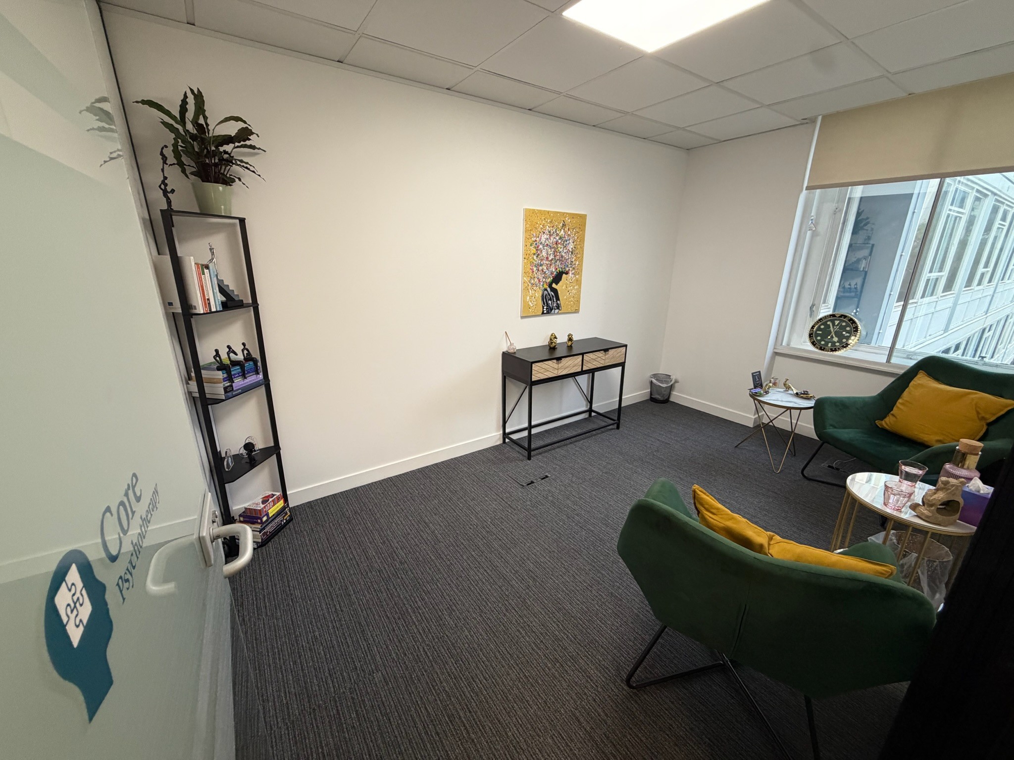 Core Psychotherapy therapy room with green chairs, a bookshelf and natural light at 4 Bedford Park in Croydon