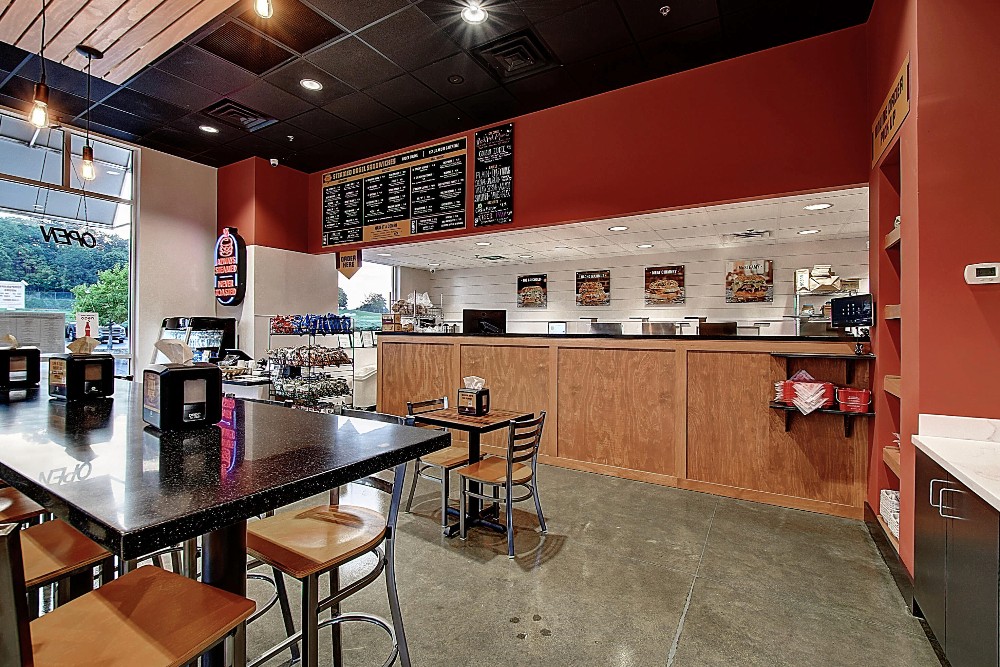 A cozy café interior featuring wooden tables, chairs, and a brightly colored wall with a coffee counter in the background.