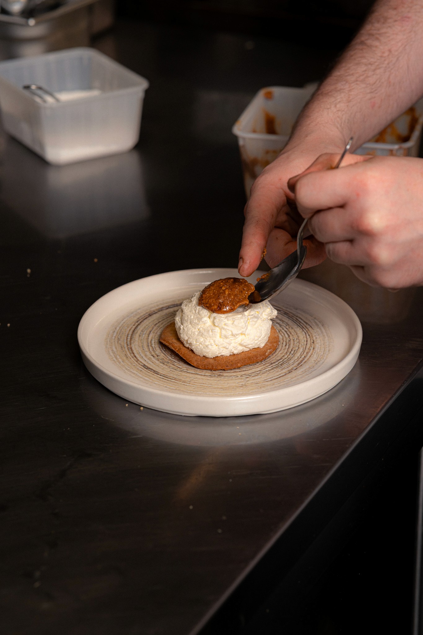Dressage d’un dessert gourmand sur biscuit croustillant, représentant le travail précis et la créativité du chef dans la cuisine du restaurant.