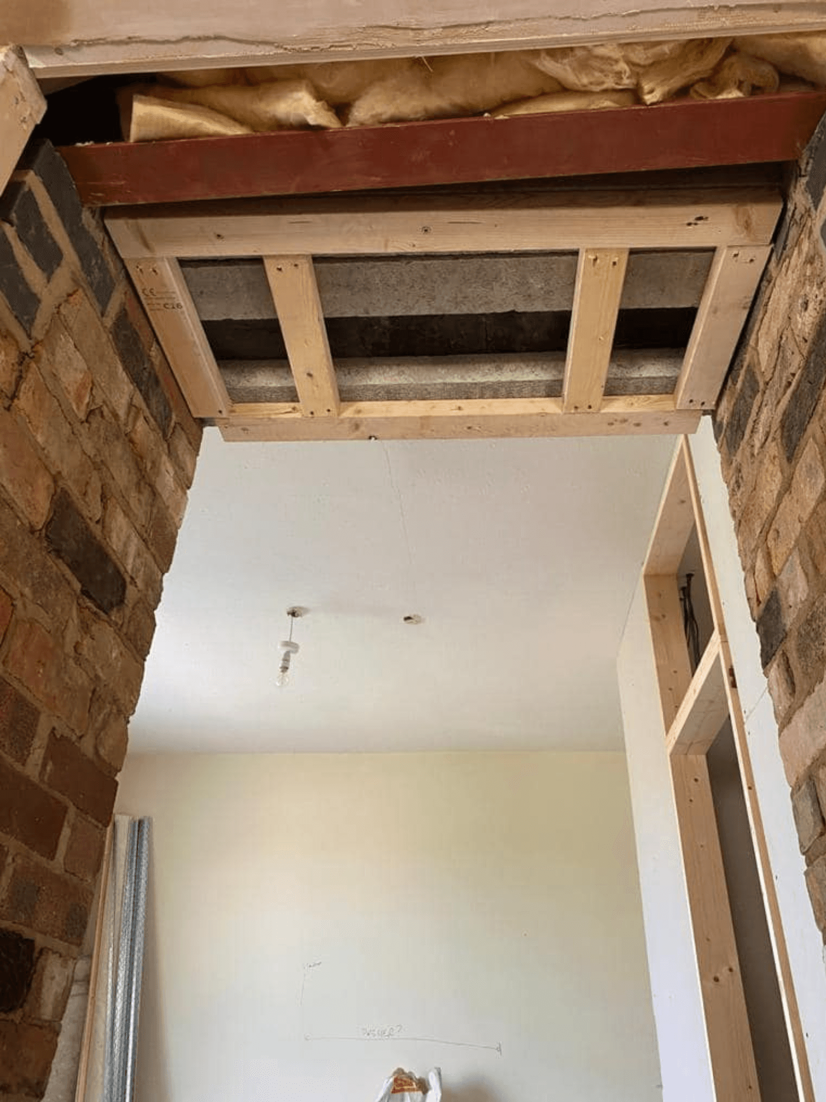 Structural framing for a new plasterboard archway by PPM Builders, showing timber reinforcement and insulation.