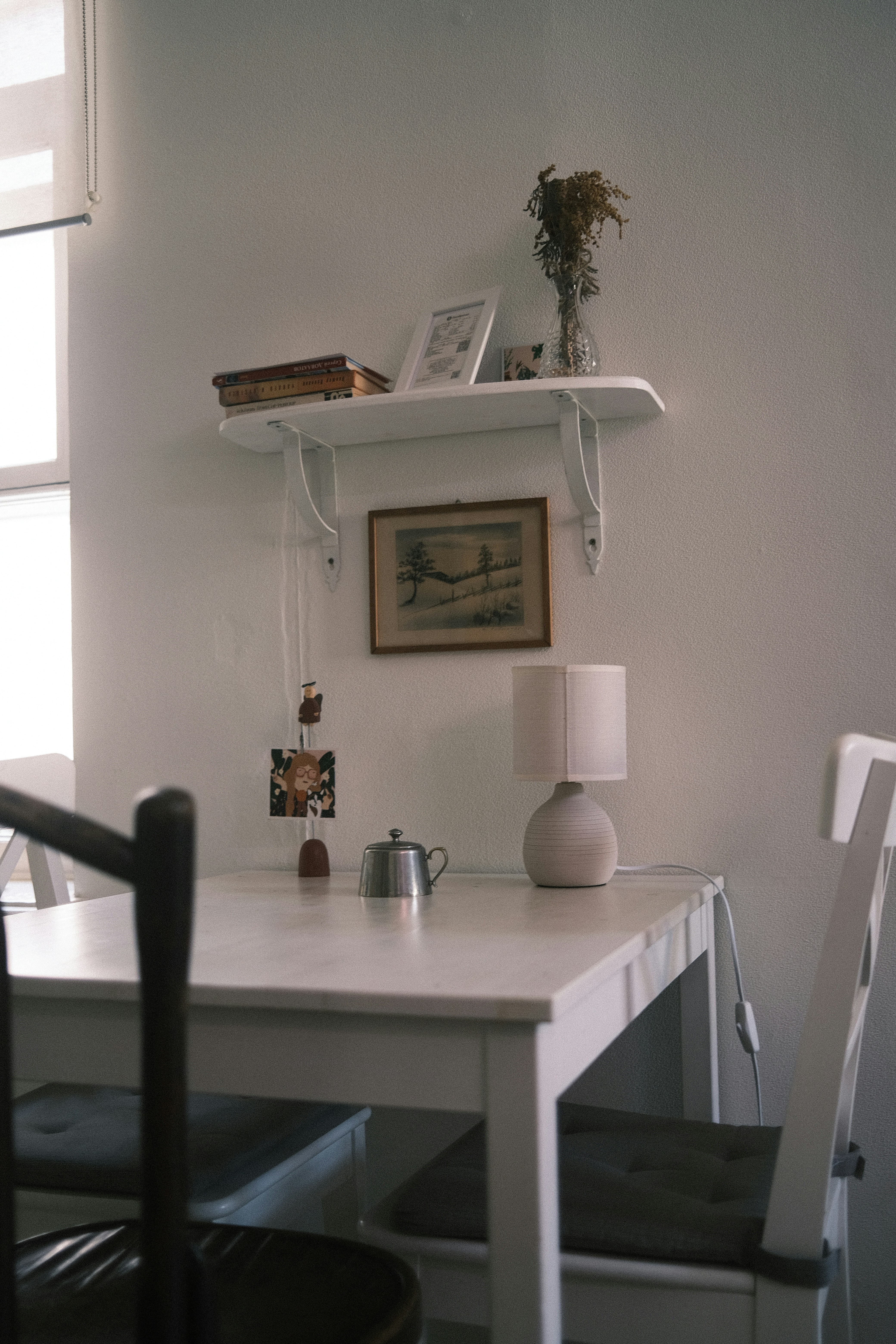 a white table with a lamp and a shelf with books on it