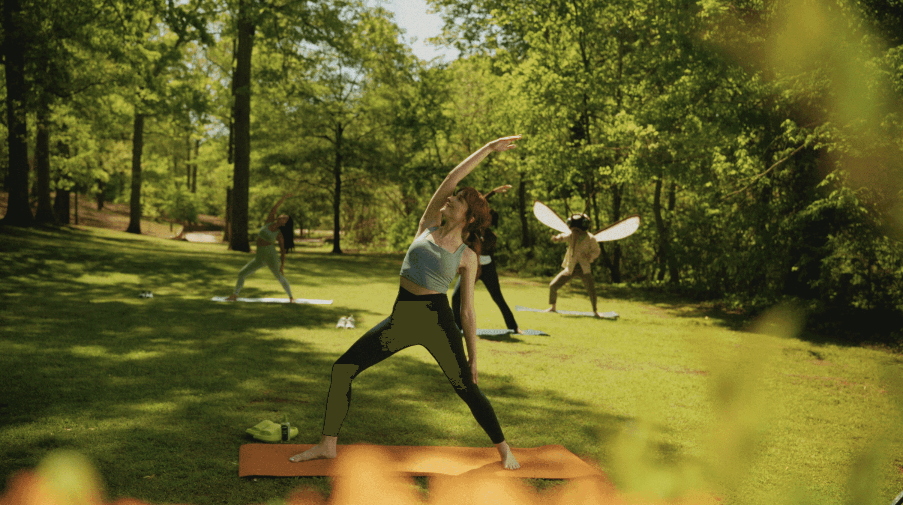 A person throws a frisbee in a green park, surrounded by trees and sunlight, with movement and joy.