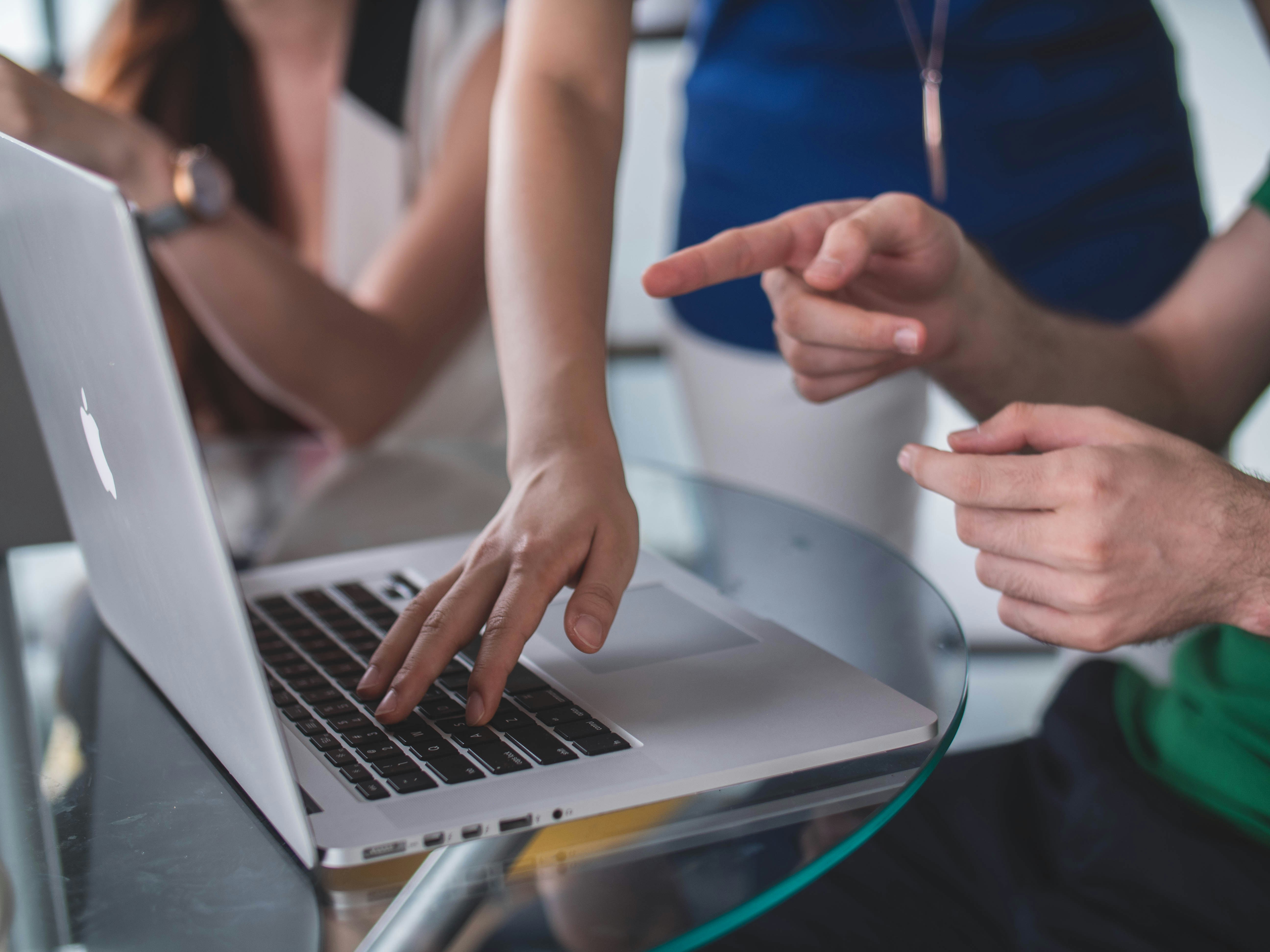 Several people are pointing at a laptop screen.