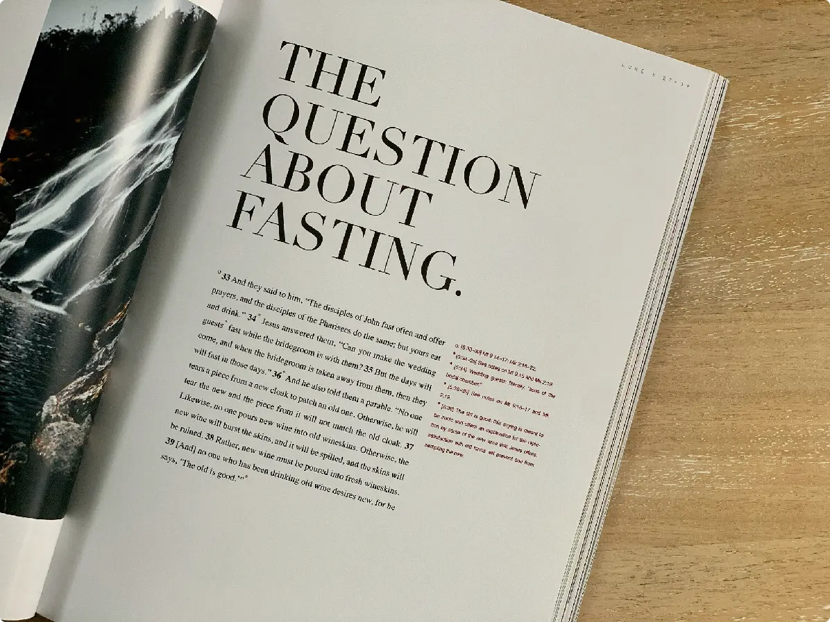 A close-up of an open book page titled "The Question About Fasting." The text is partially visible against a wooden surface.