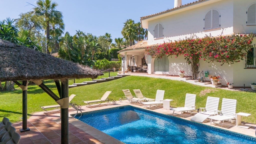 Inviting outdoor pool area surrounded by mature gardens in the exclusive villa located on Marbella's Golden Mile.