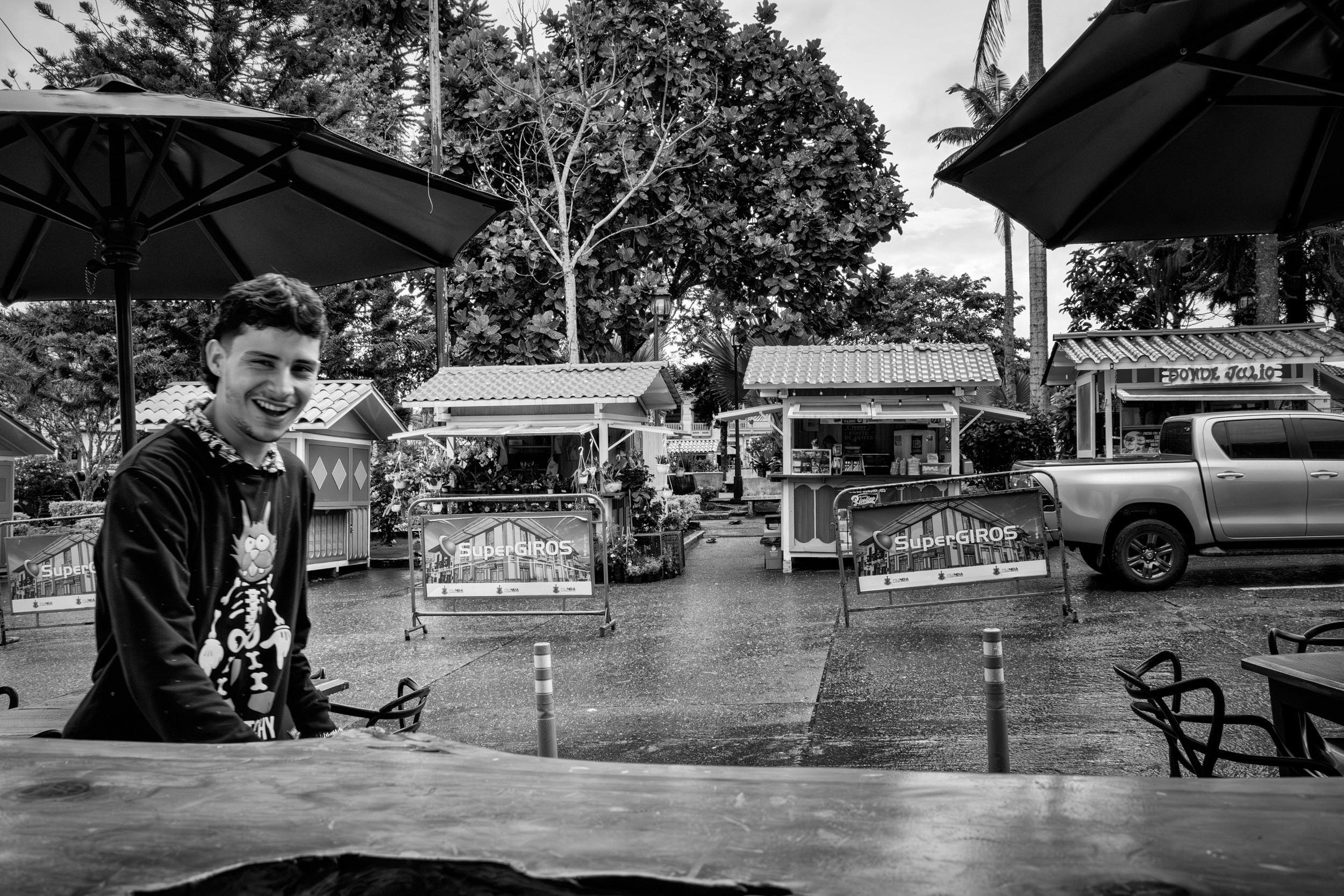 Rainy street scene with people passing by a bar window.