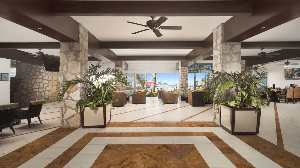 Couple standing on a balcony with binoculars in hand looking out over the ocean