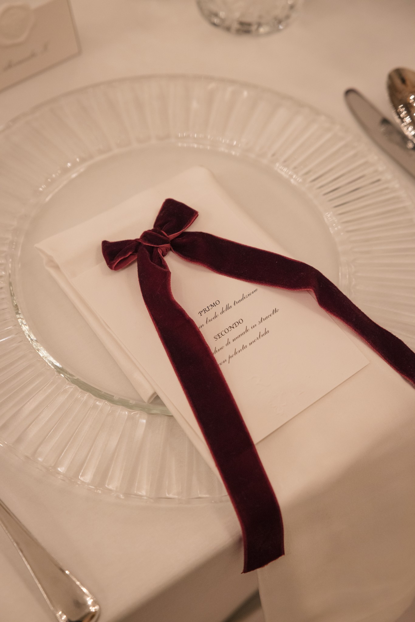 Menù matrimoniale con fiocco in velluto bordeaux sul piatto bianco, ricevimento al Circolo di Lettura a Parma