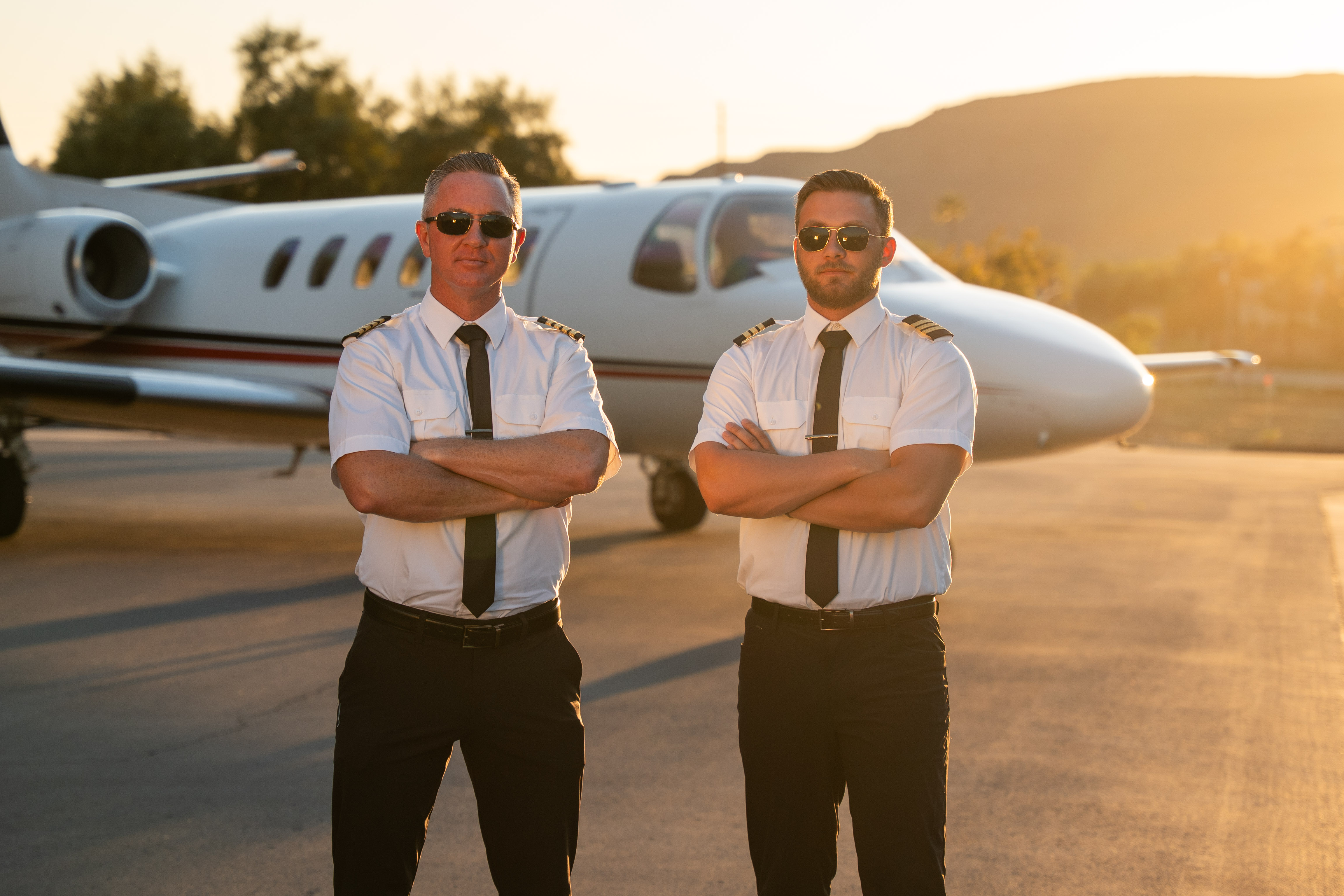 Three colleagues sitting around a table, smiling and discussing work with laptops open in front of them during a team meeting.