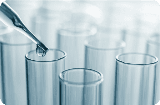 A dropper placing a drop of liquid into one of several test tubes