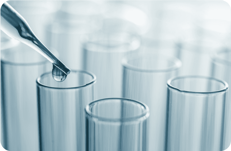 A dropper placing a drop of liquid into one of several test tubes