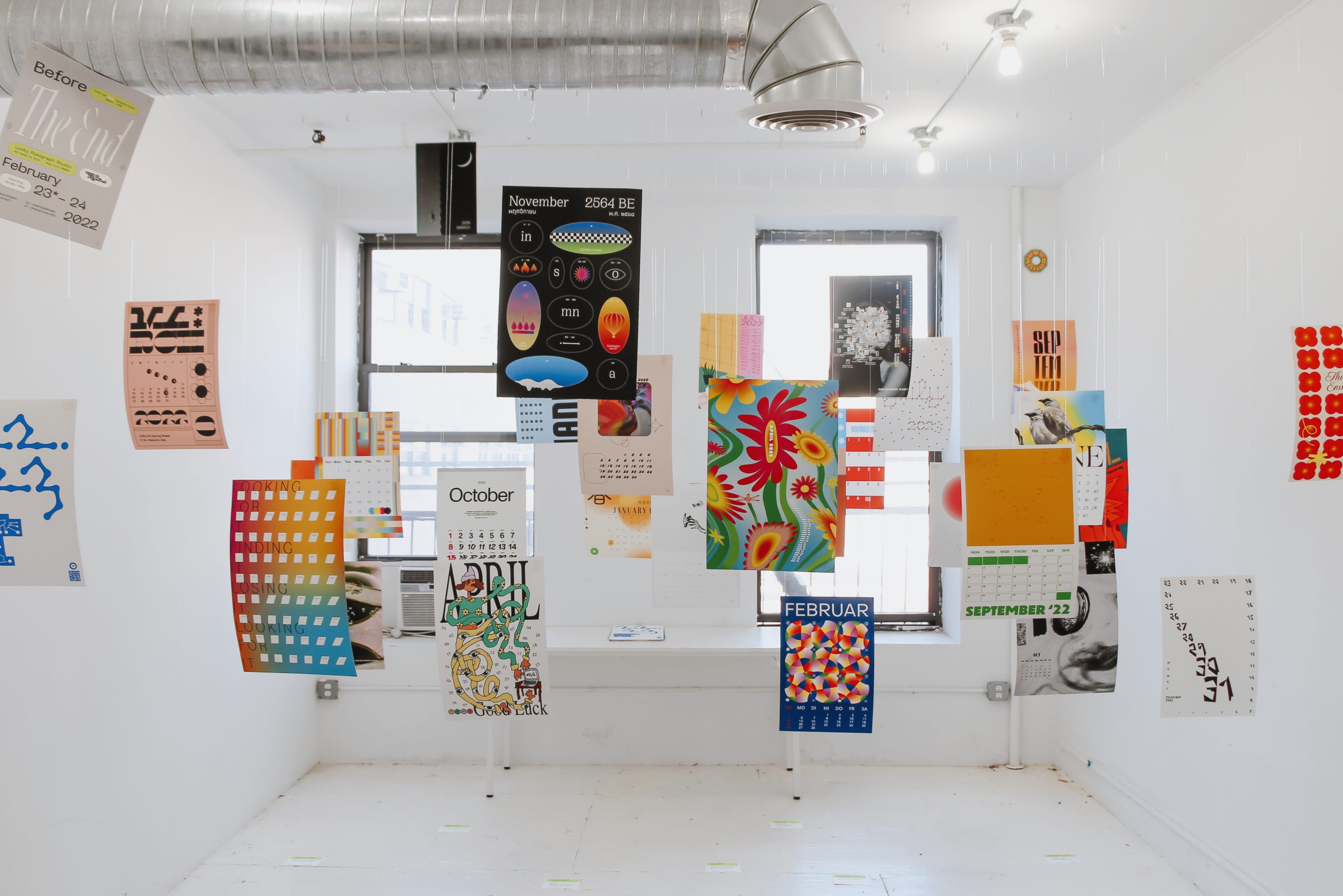 Exhibition with multiple multi-colored posters hanging from the ceiling