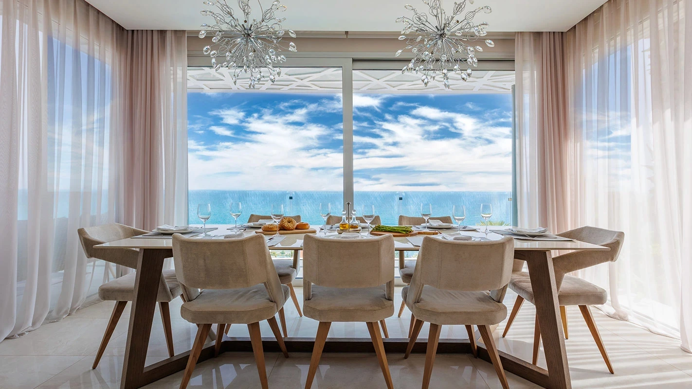 Seafront Residence Limassol dining area with ocean-view glazing, timber table, and soft neutral seating
