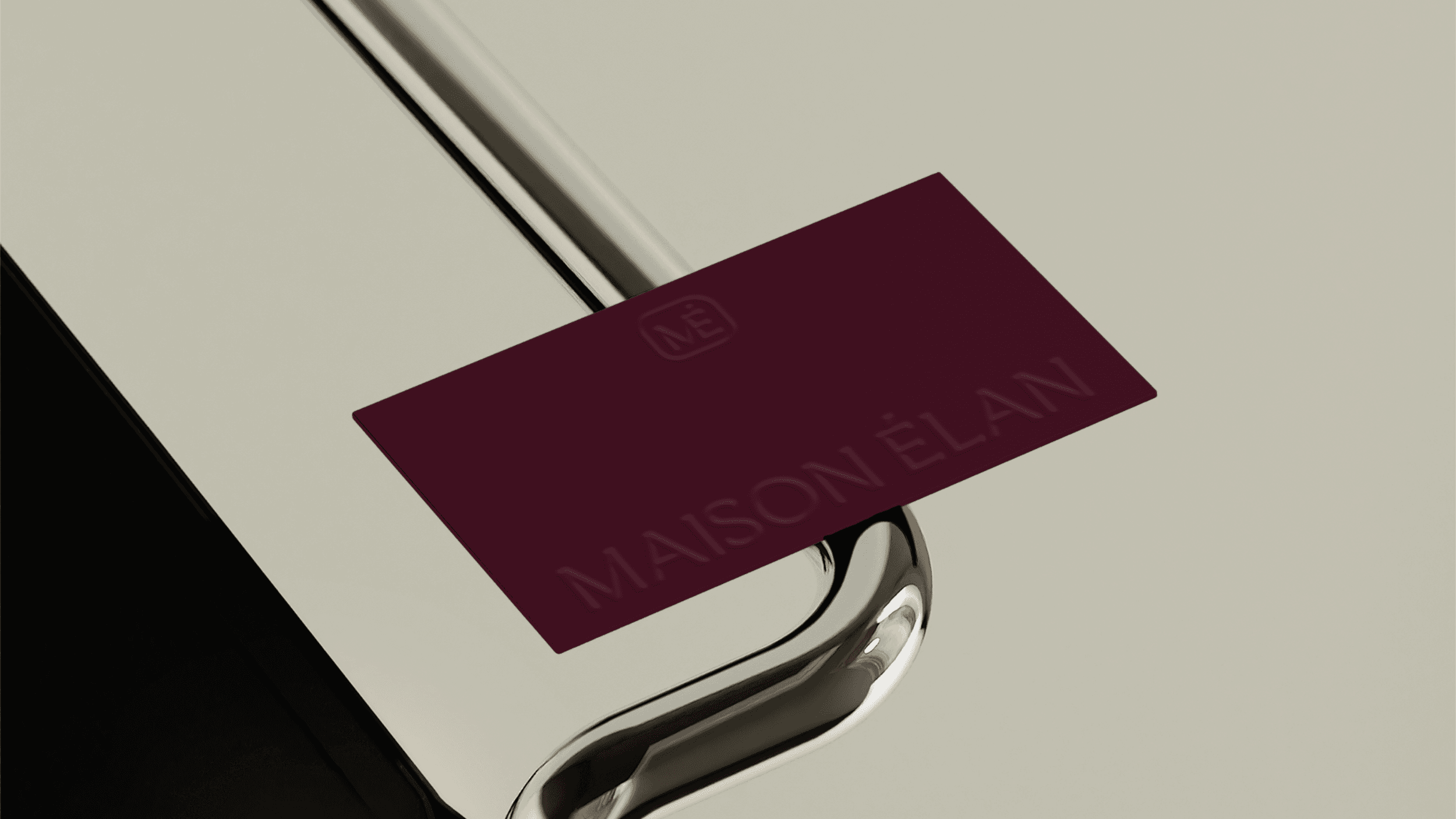A Maison Élan business card. The card is burgandy with the brand logo embossed on it.