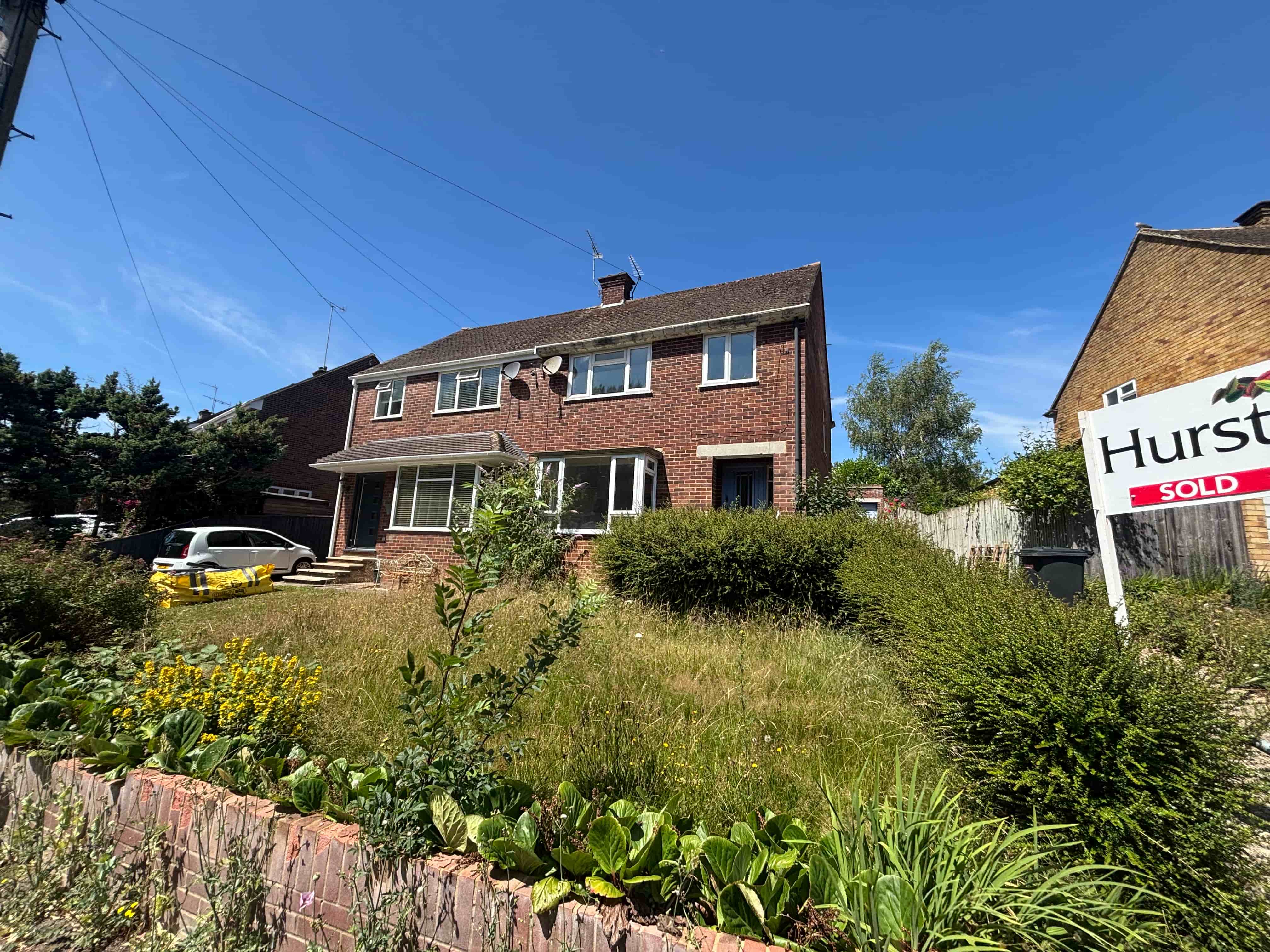 : Garden path through modern black wooden pergolas leading to a green shed.