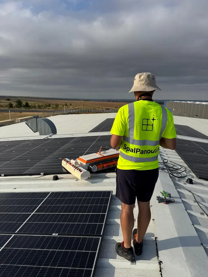 Tehnician SpalPanouri operând un robot de curățare pe acoperișul unei hale industriale