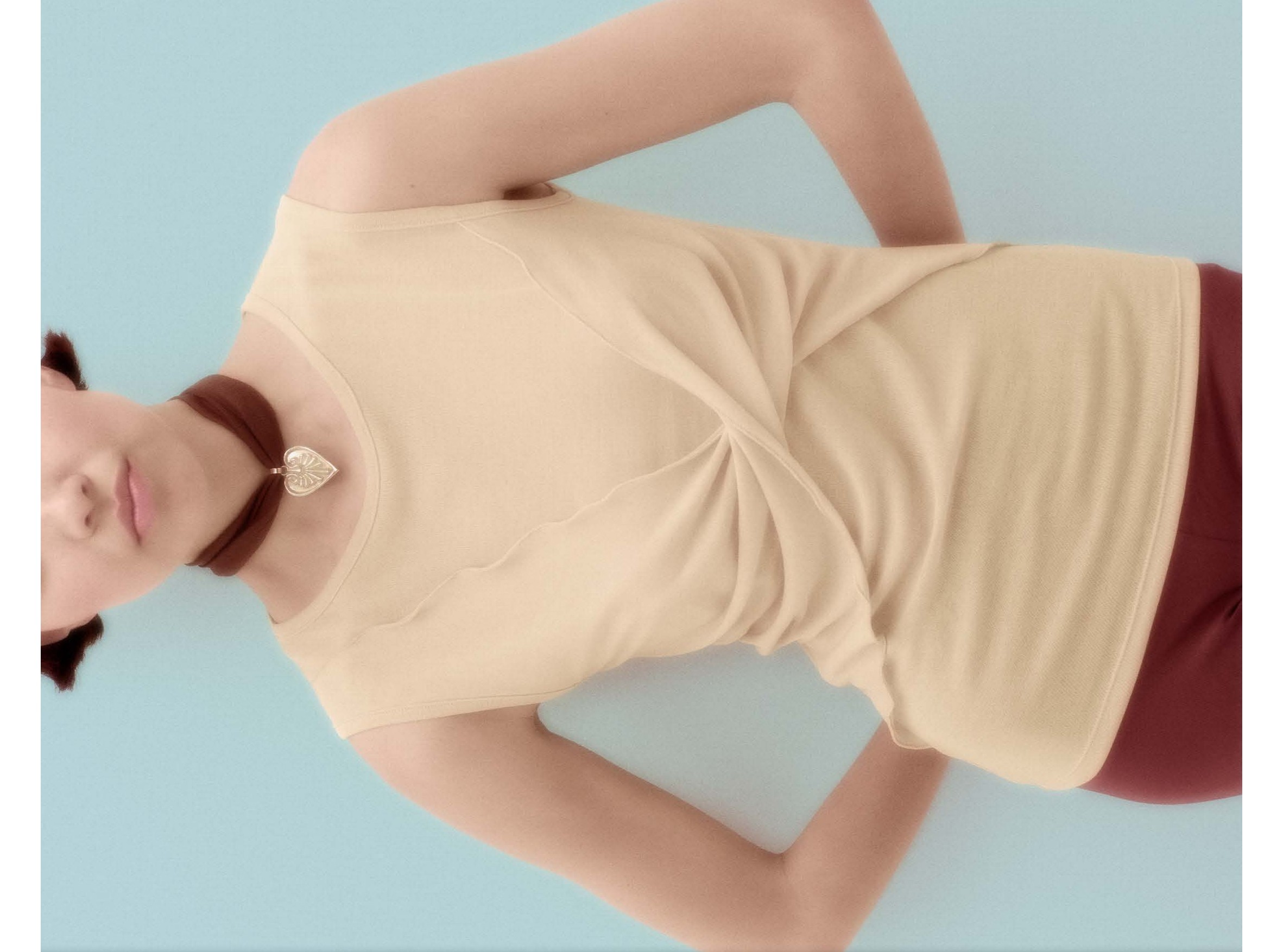 Photo de détail d'un lookbook mode, la mannequin porte un top beige sur fond bleu clair