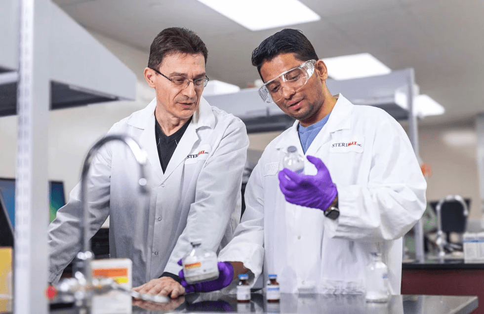 Two SteriMax scientists examine vials on a laboratory table.
