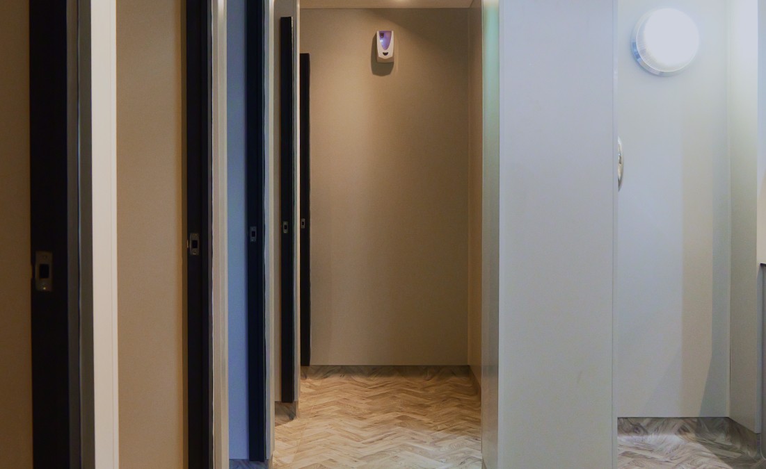 Completed commercial washroom corridor with modern cubicles, clean wall finishes and herringbone-style flooring.