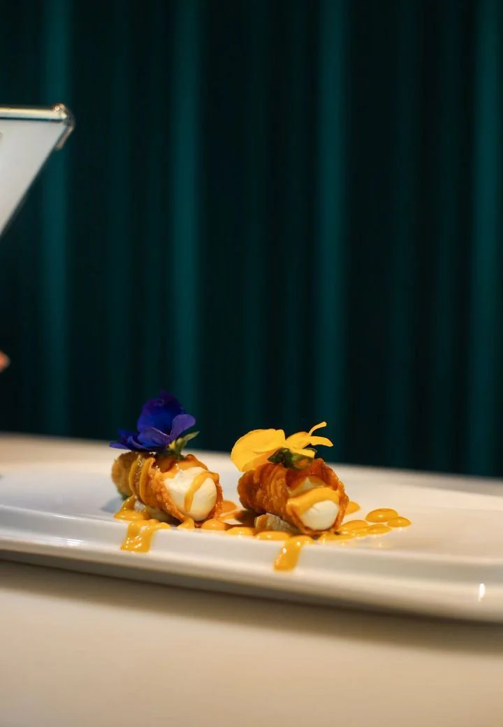 Deux bouchées dressées avec des fleurs comestibles sur une assiette blanche