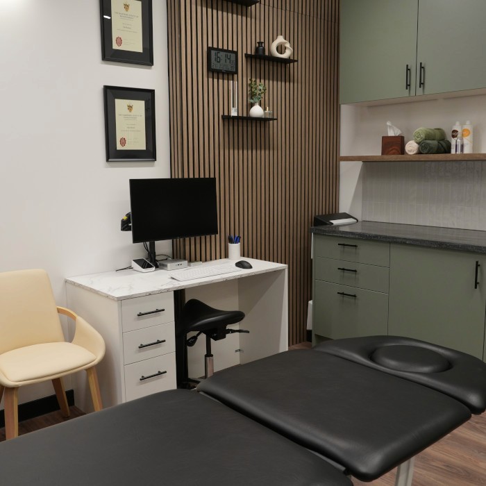 Modern physiotherapy studio with treatment bed, char, desk, and computer