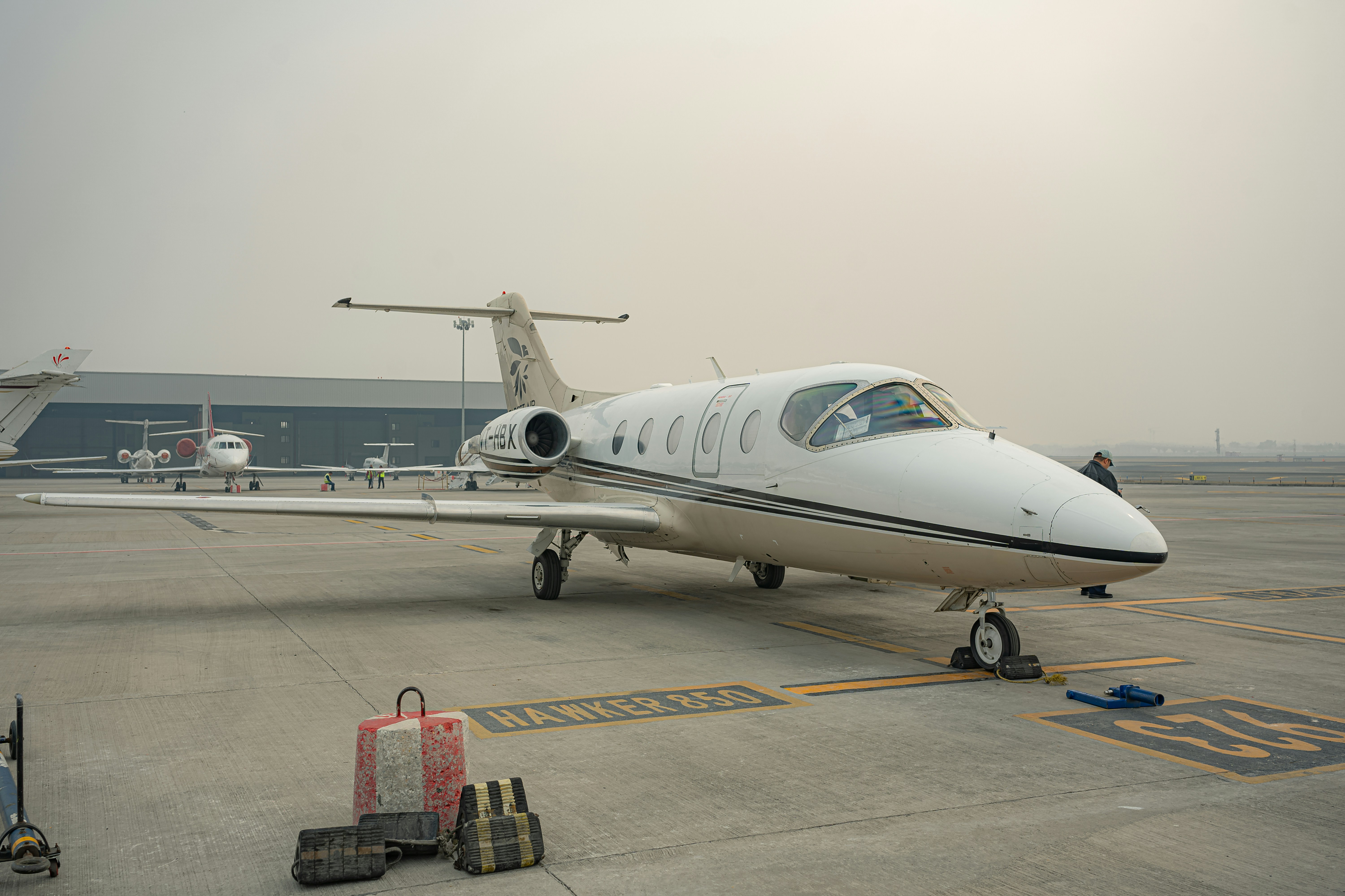 A white private jet parked on an airport tarmac.